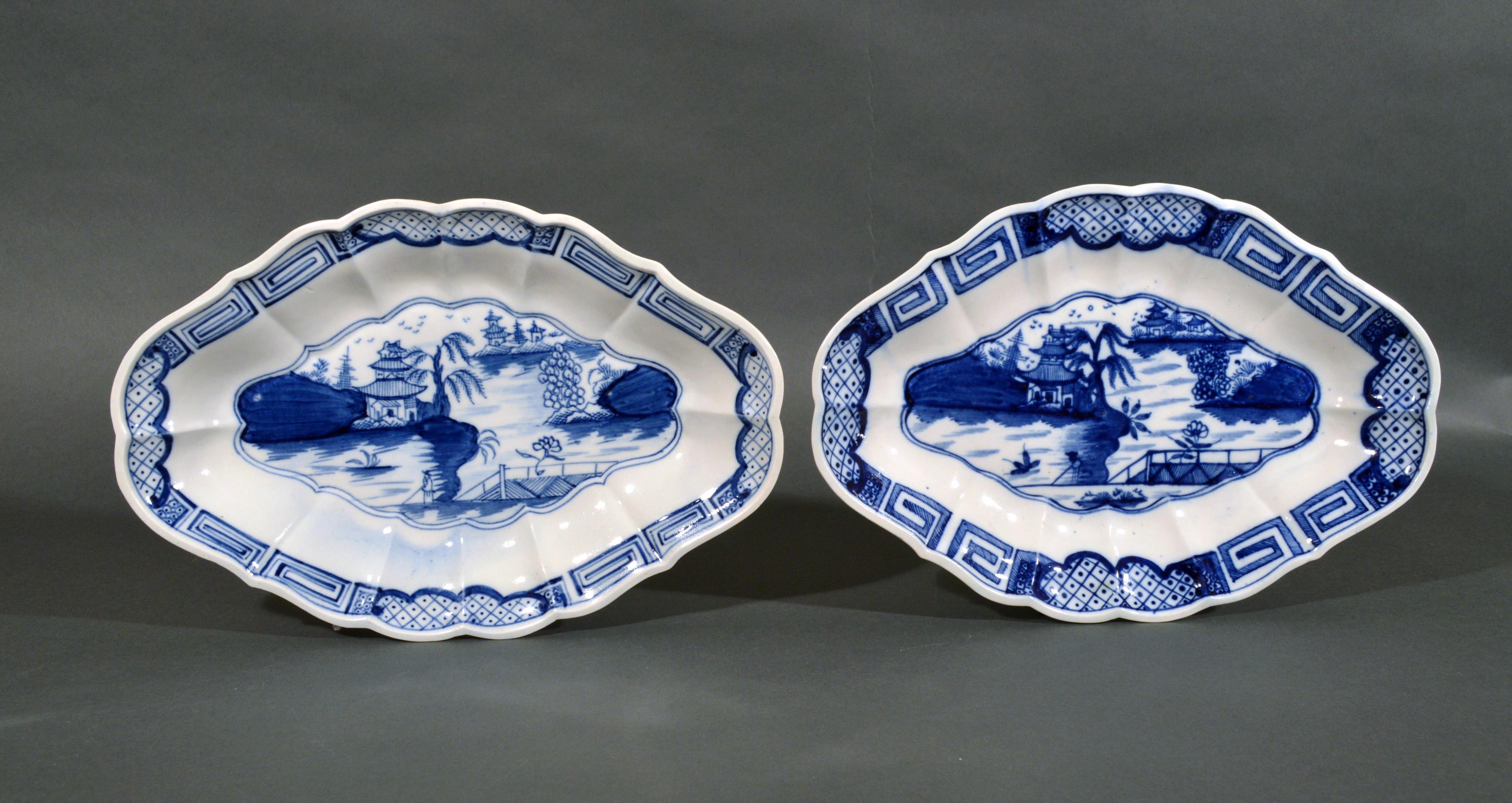 18th Century British porcelain Caughley painted chinoiserie shaped dishes,
circa 1785-1793.

The pair of shaped oval dishes are painted in the center with a chinoiserie scene of a pagoda by a lakeside and others in the background and a solitary