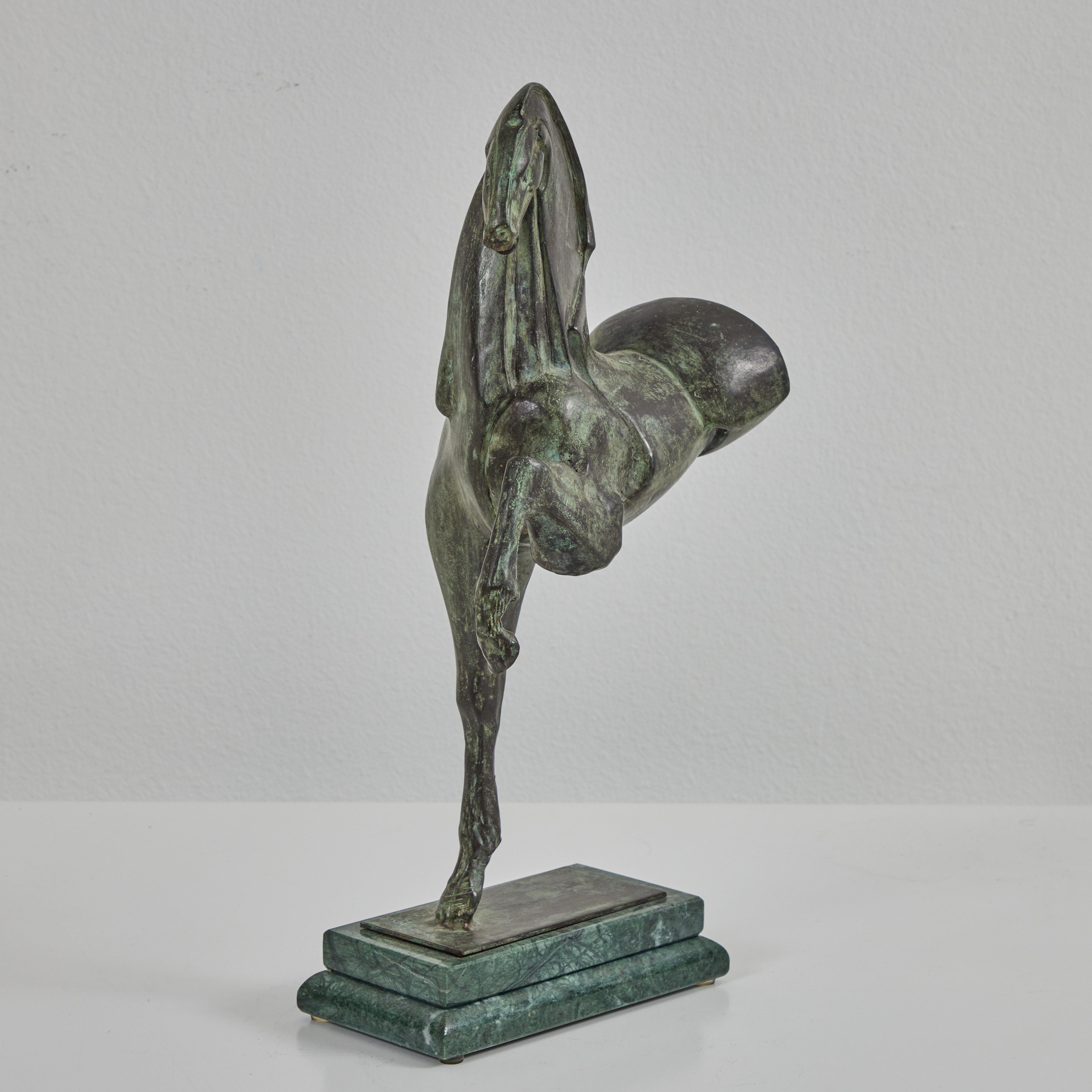 This sculpture by Claudio Nicoli portrays an astute horse balanced on one front leg. The scattered application of patina gives the appearance of a rich texture. It is secured onto a marble base. The piece is signed by Nicoli on the back of the