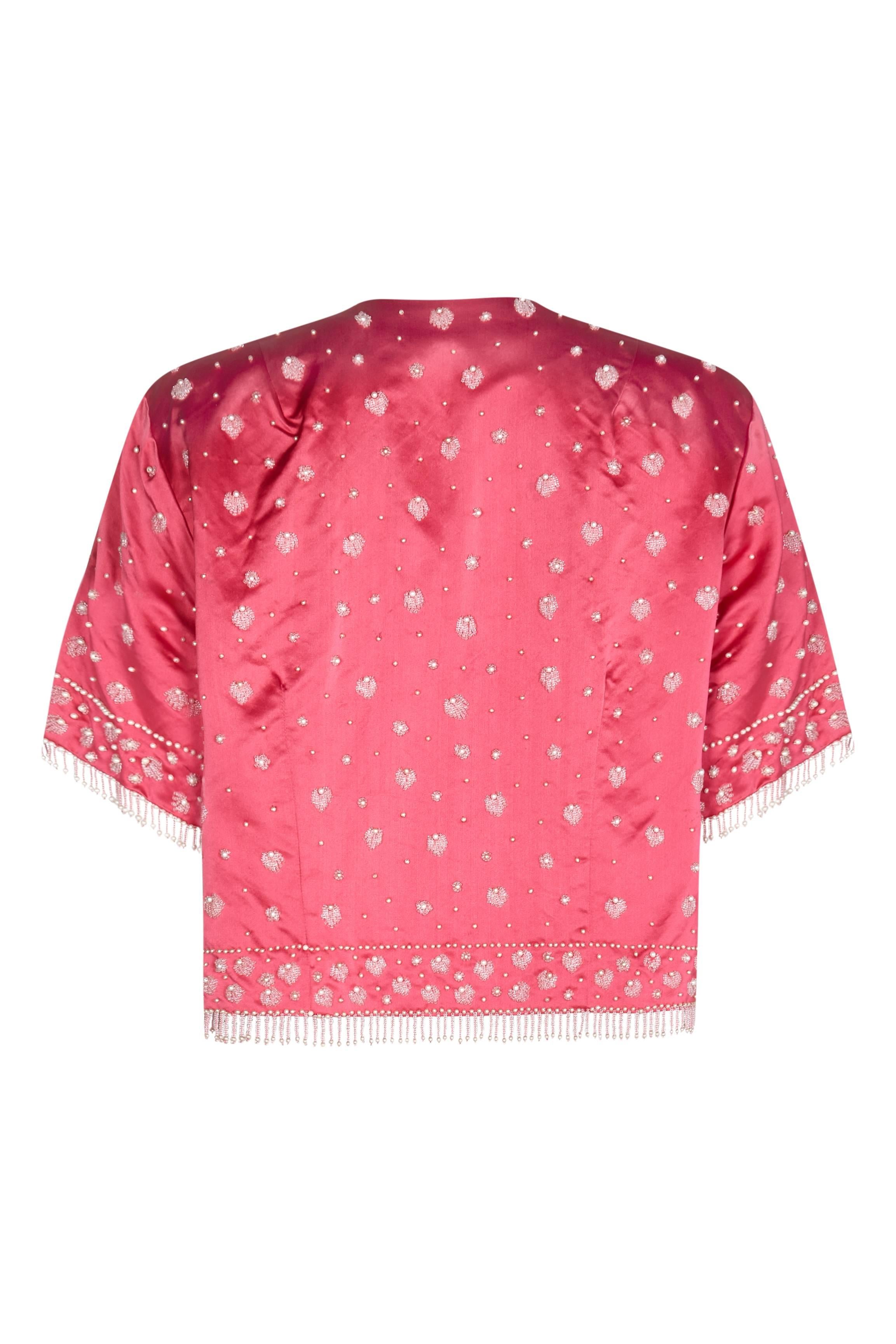 Cette charmante veste de soirée en soie des années 1950, ornée de perles, porte l'étiquette de Cavanagh's de St Thomas, dans les îles Vierges, qui aurait été la boutique de référence de cette destination glamour à cette époque. La veste, qui va
