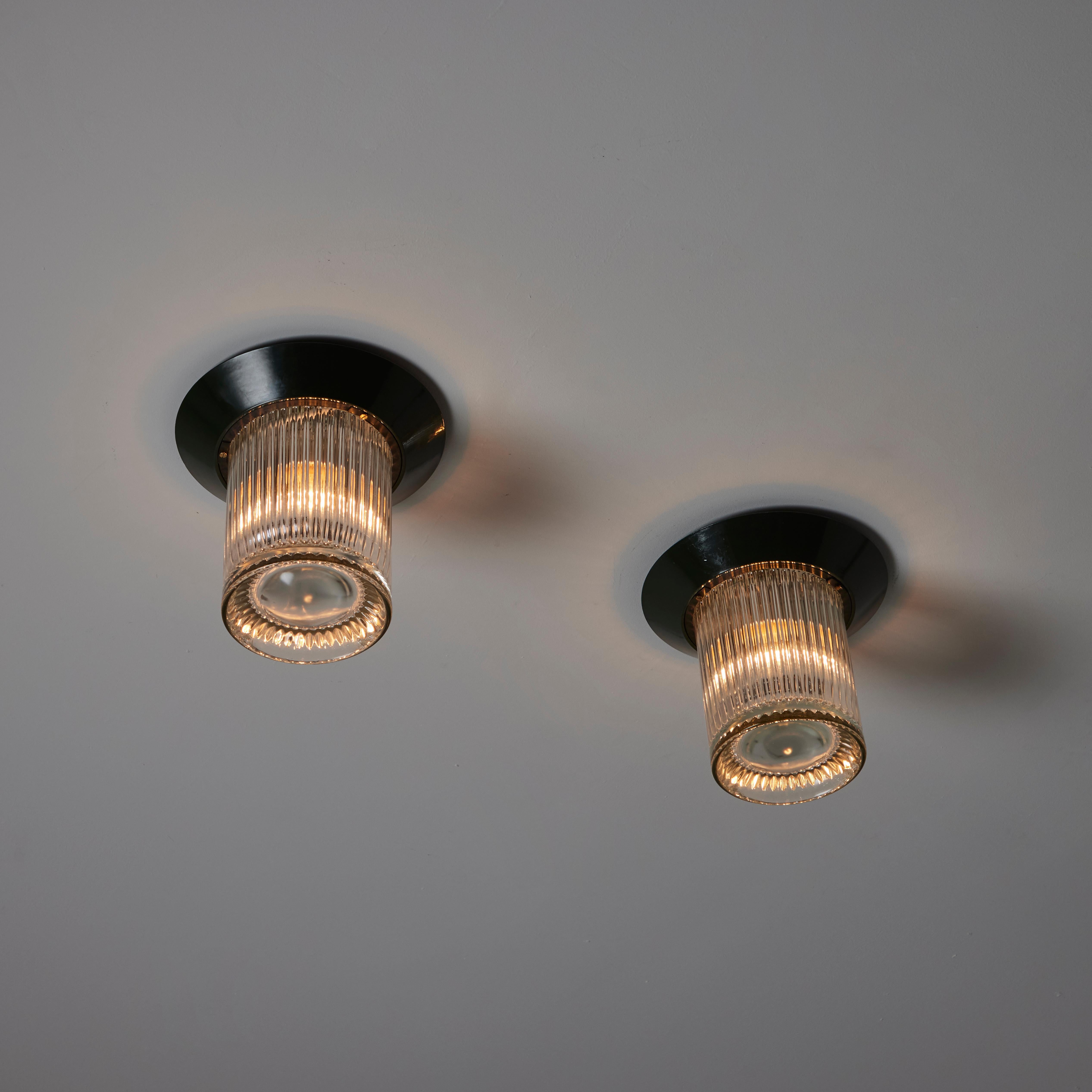 'Cavea' Flushmounts by Angelo Mangiarotti for Artemide. Designed and manufactured in Italy, circa the 1970s. Cylindrical reeded glass paired with enameled forest green mounting plates. Each light holds a single E27 socket-type, adapted for the US.