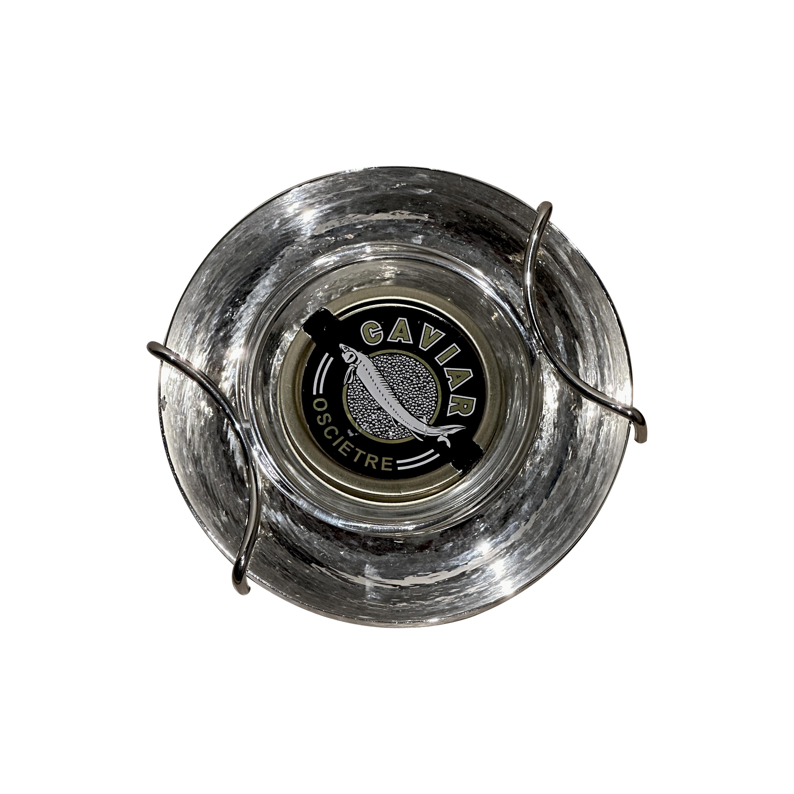 Un servidor de caviar bañado en plata martillada a mano con interior de cristal, diseñado para mantener el caviar a la temperatura ideal. Su elegante diseño resalta la artesanía italiana con una textura suave única que combina tradición y