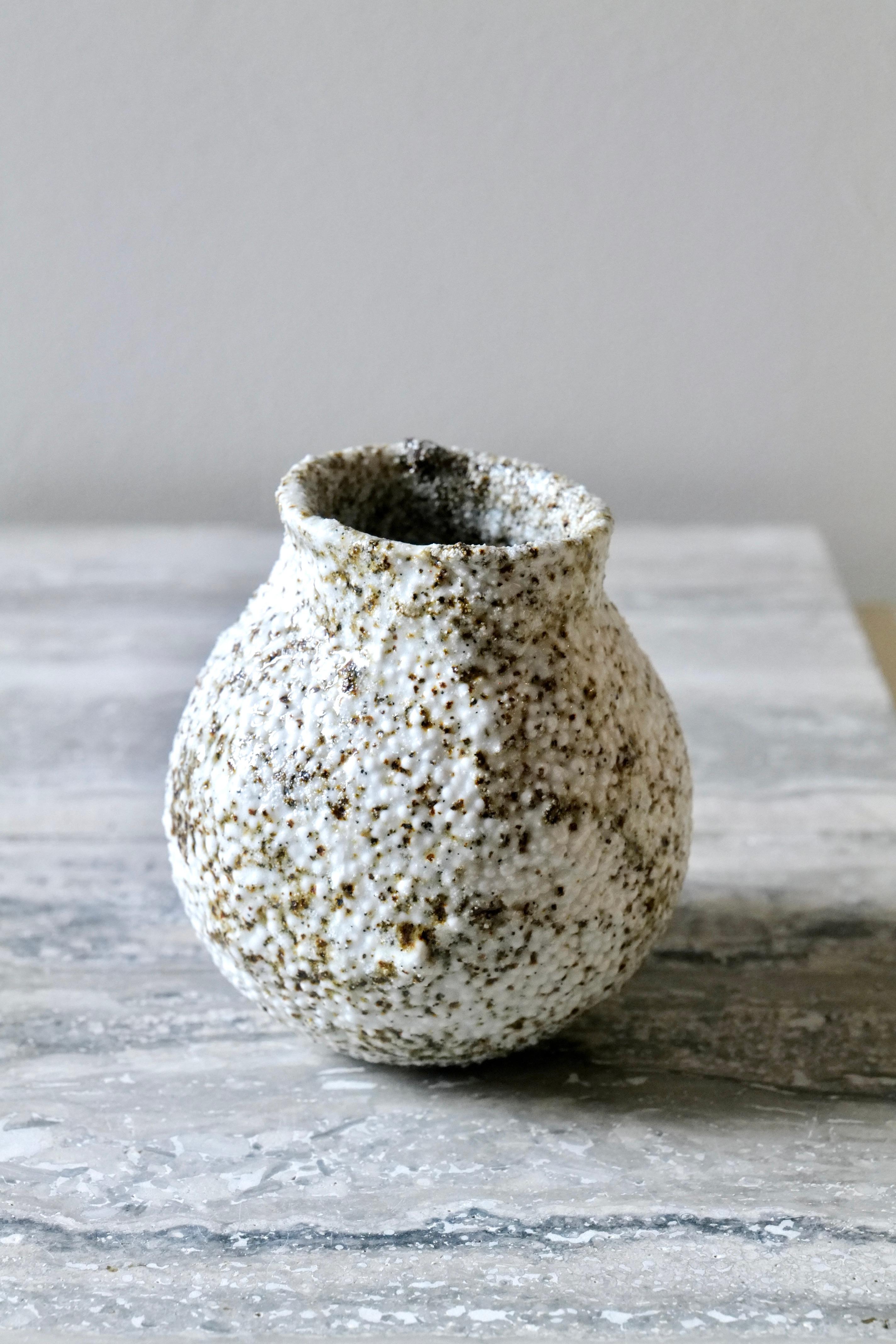 Caviar Porcelain Small Vase is an exquisite handcrafted piece inspired by nature’s organic textures and earthy tones. Its transparent glaze is speckled with local sand blending varied brown and gray specks colors with soft white to create a warm,