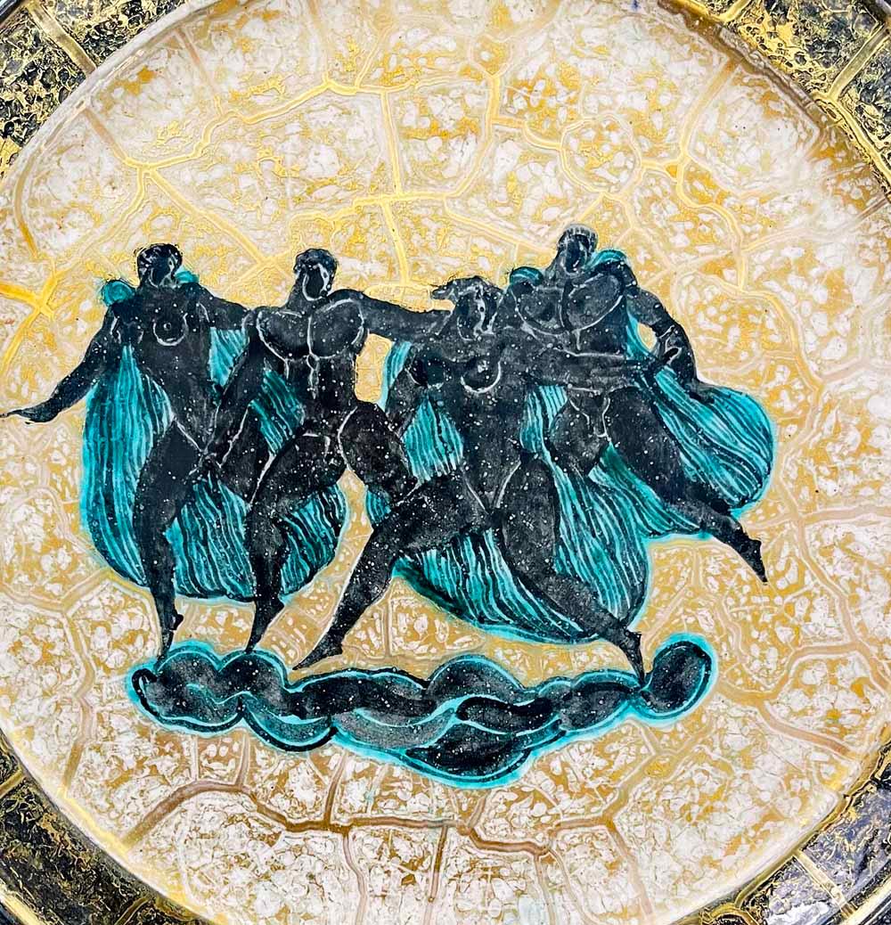 Joyous and buoyant, this scene of four nude gods and goddesses, each with blue striped capes, cavorting in the clouds above, was designed and executed by the great Jean-Leon Mayodon for the legendary Sèvres porcelain works.  The figures are glazed
