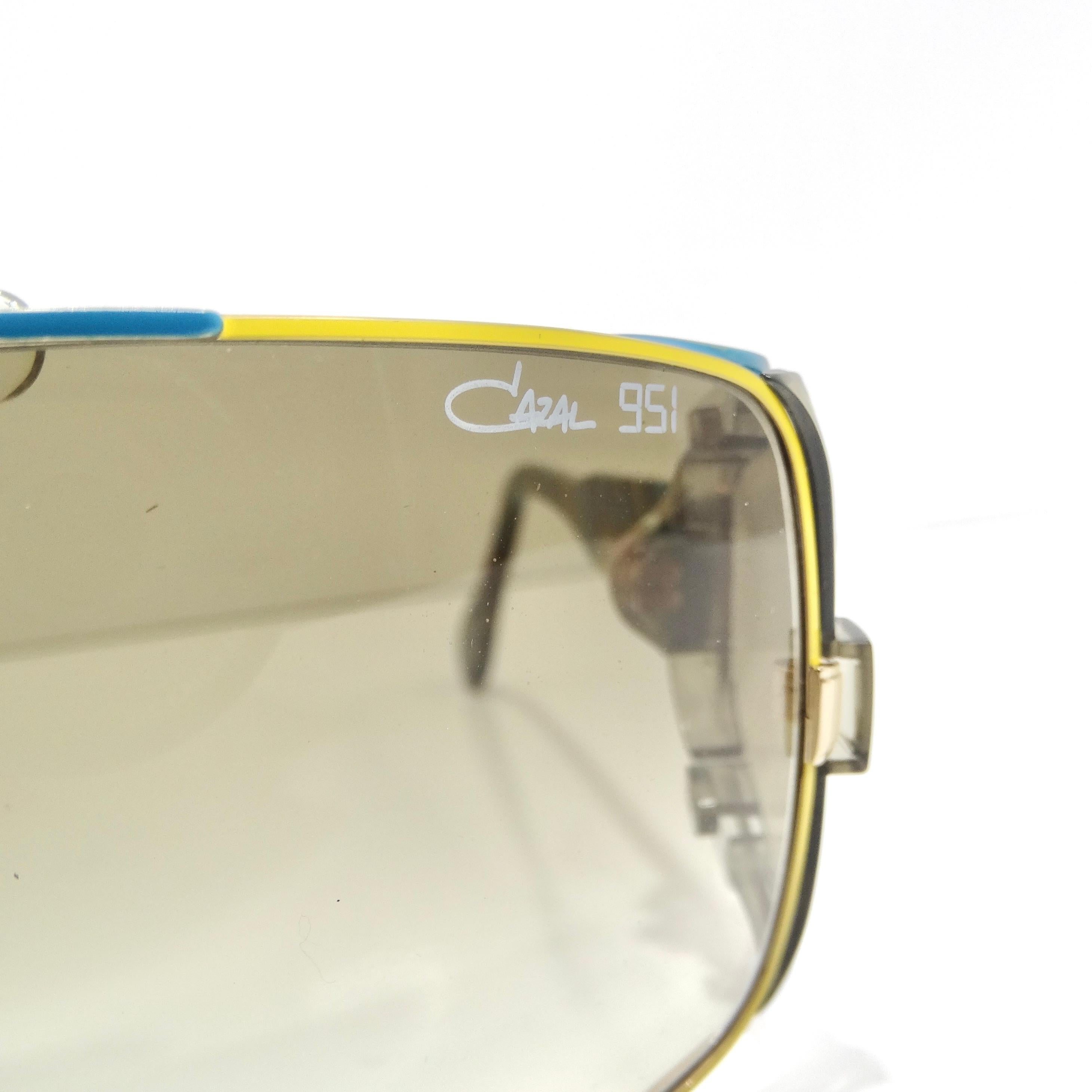 Introducing the Cazal 951 Limited Edition Sunglasses, a striking and super unique addition to your eyewear collection. These sunglasses are crafted with meticulous attention to detail, featuring rectangular lenses adorned with thin yellow and blue