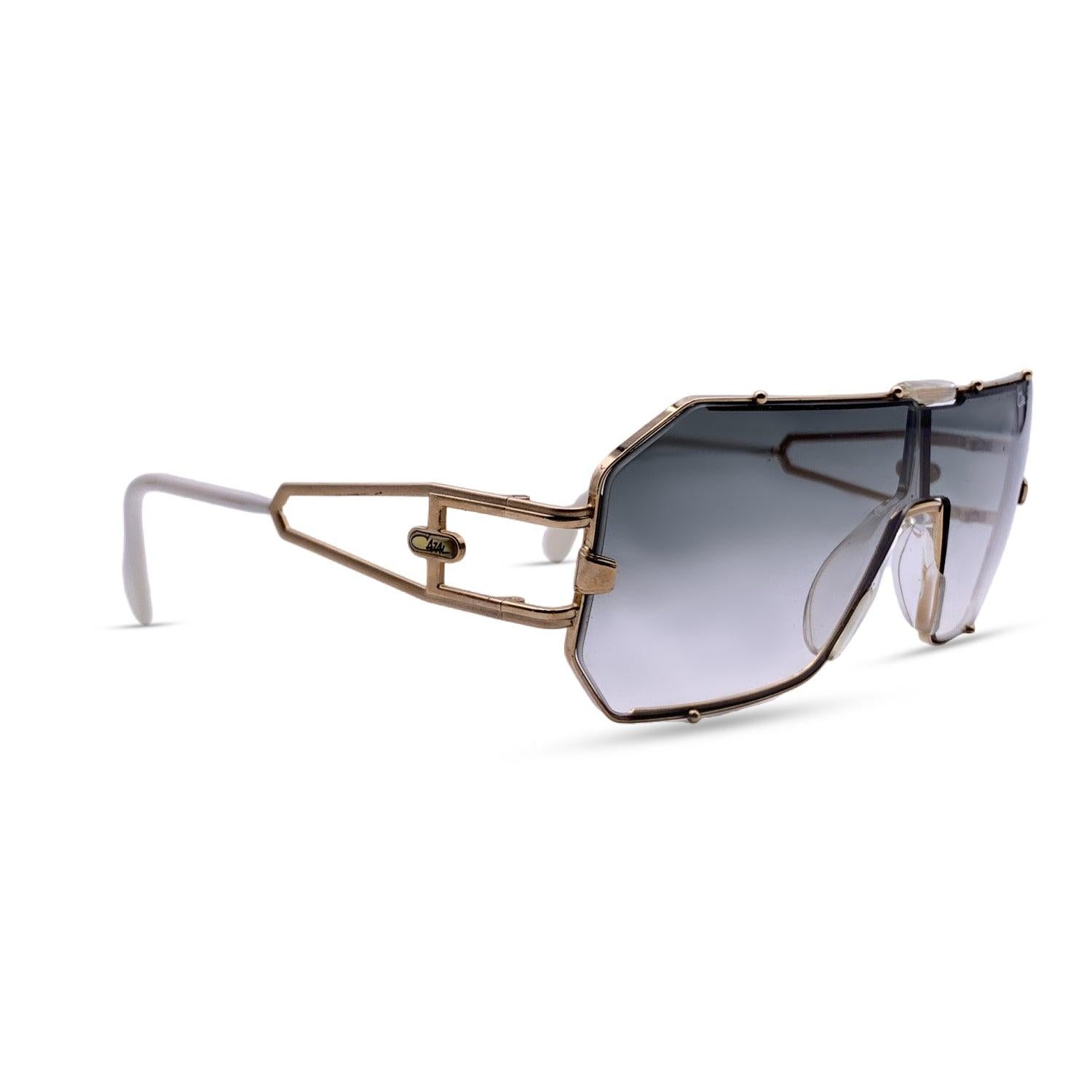 Beautiful sunglasses by Cazal, Mod. 904 Col. 97. Shield frame. Gradient one piece lens in grey color. This model has an interchangeable lens system (brown lens included). Gold metal frame. Cazal logo on temples. Made in W.Germany. Details MATERIAL: