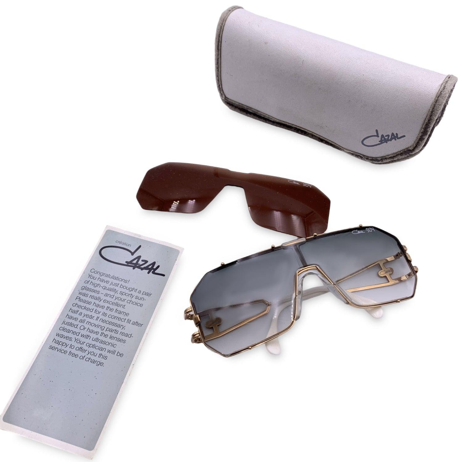 Beautiful sunglasses by Cazal, Mod. 904 Col. 97. Shield frame. Gradient one piece lens in grey color. This model has an interchangeable lens system (brown lens included). Gold metal frame. Cazal logo on temples. Made in W.Germany. Condition A+ -