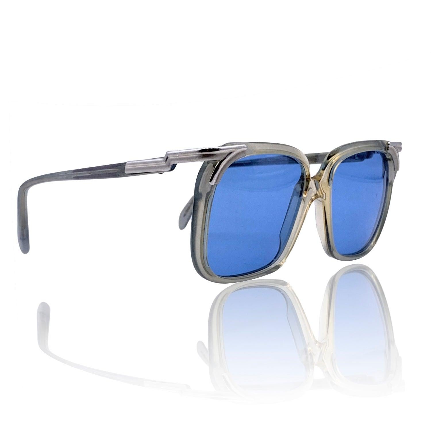 Entra en un pedazo de la historia de las gafas con estas icónicas gafas de sol vintage de Cazal, modelo 112 col. 01. Con una llamativa montura gris transparente que desprende un encanto discreto y desenfadado, estas gafas de sol son un verdadero