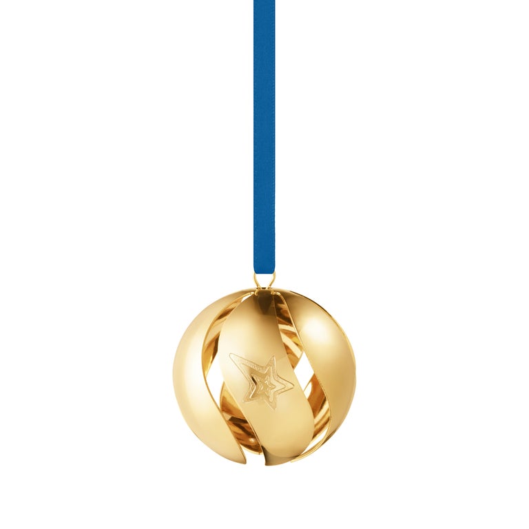 Georg Jensen’s signature 18 karat gold plated Christmas bauble decoration is this year decorated with a stylised shooting star - a symbol of optimism and transient beauty. The open swirl cut outs reveal a polished gold interior that catches the