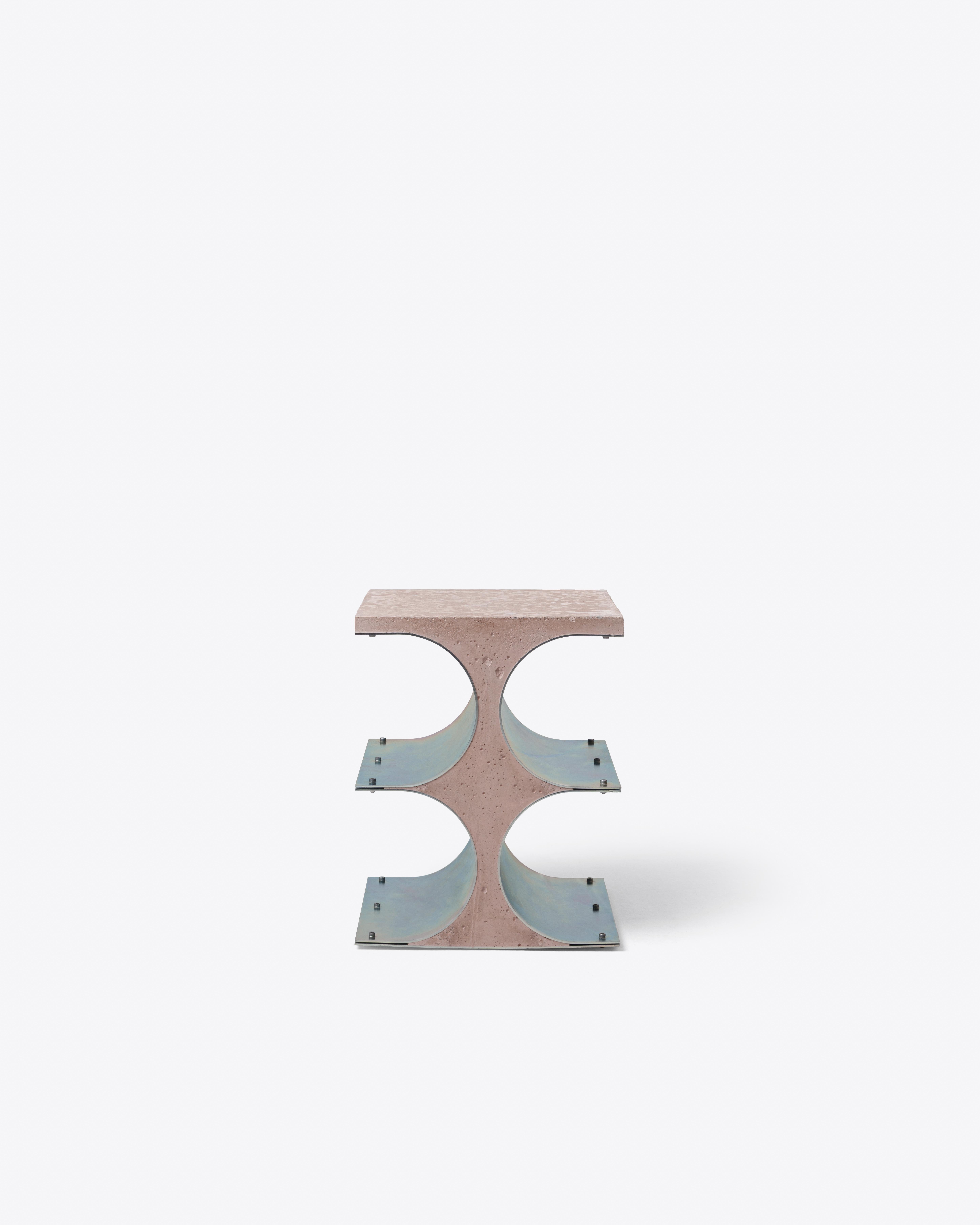 This side table combines a cast spine with two curved galvanized steel panels, creating a bold negative space t its core. Visible bolts expose the construction, giving the piece tectonic clarity. The balance of solid and void, curve and plane,