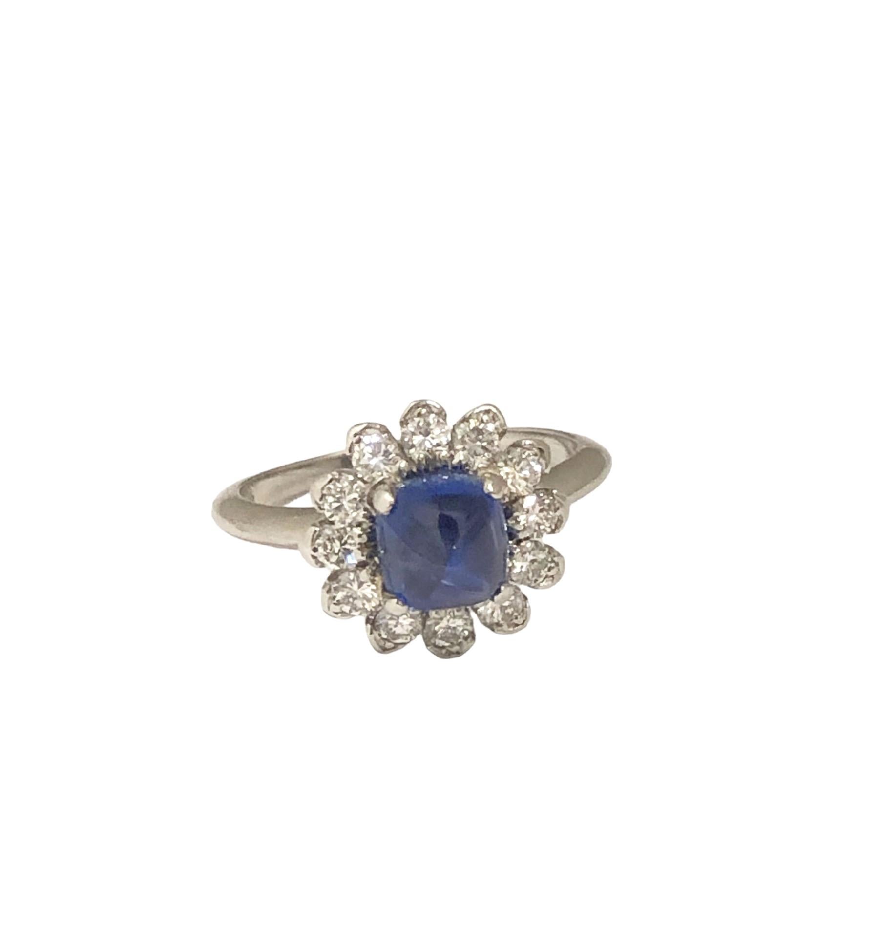 Circa 1930 C. D. Peacock Platinum Ring, Centrally set with a Fine color Sugar Loaf Cabochon Sapphire of approximately 1 carat and surrounded by 12 transitional cut Diamonds totaling .50 Carat. the top of the ring measures 1/2 inch in diameter with a
