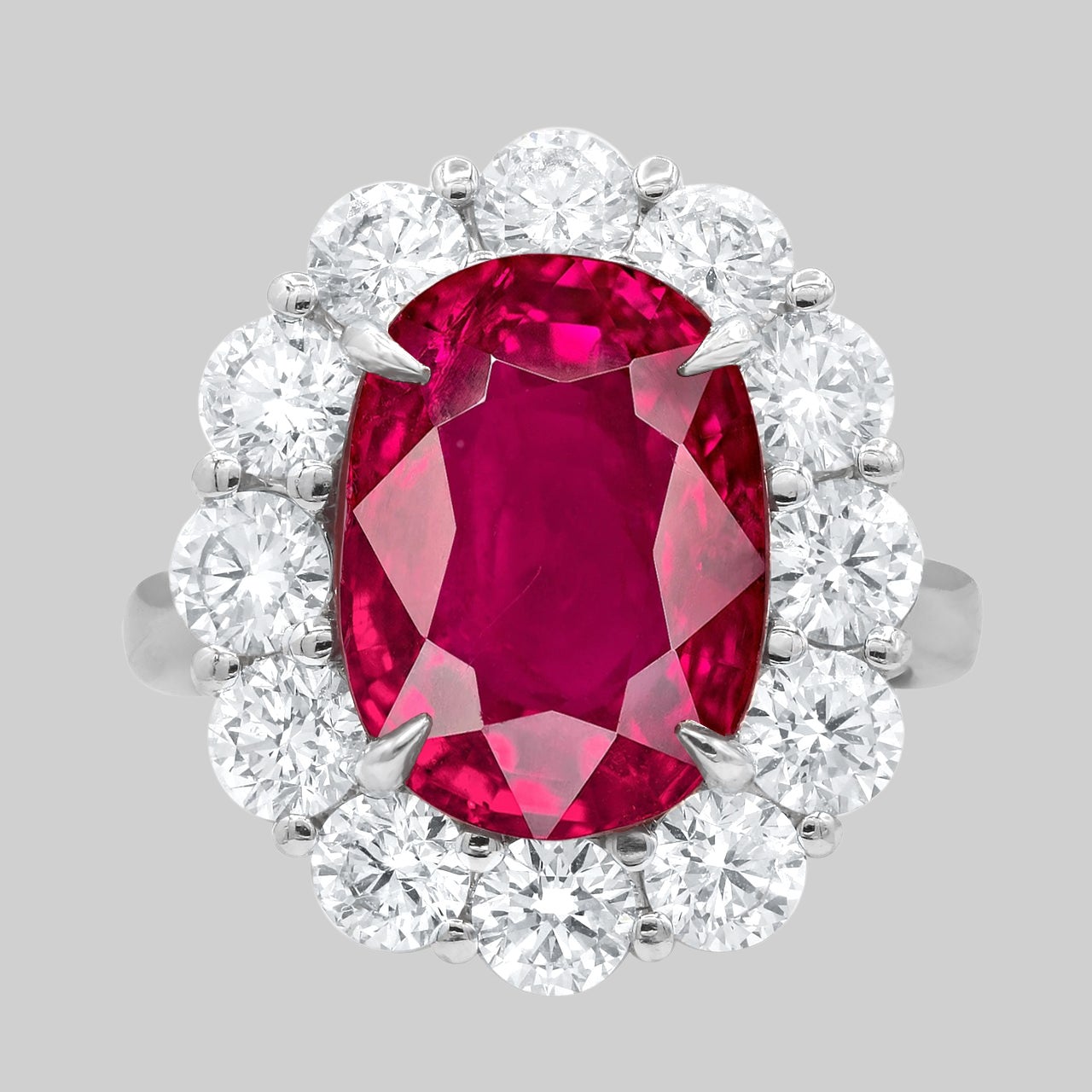 Esta exquisita gema de Rubí natural tiene una belleza cautivadora y se exhibe en un engaste artesanal hecho a medida en platino macizo. El diseño del anillo se eleva con un deslumbrante halo de diamantes redondos, meticulosamente seleccionados y