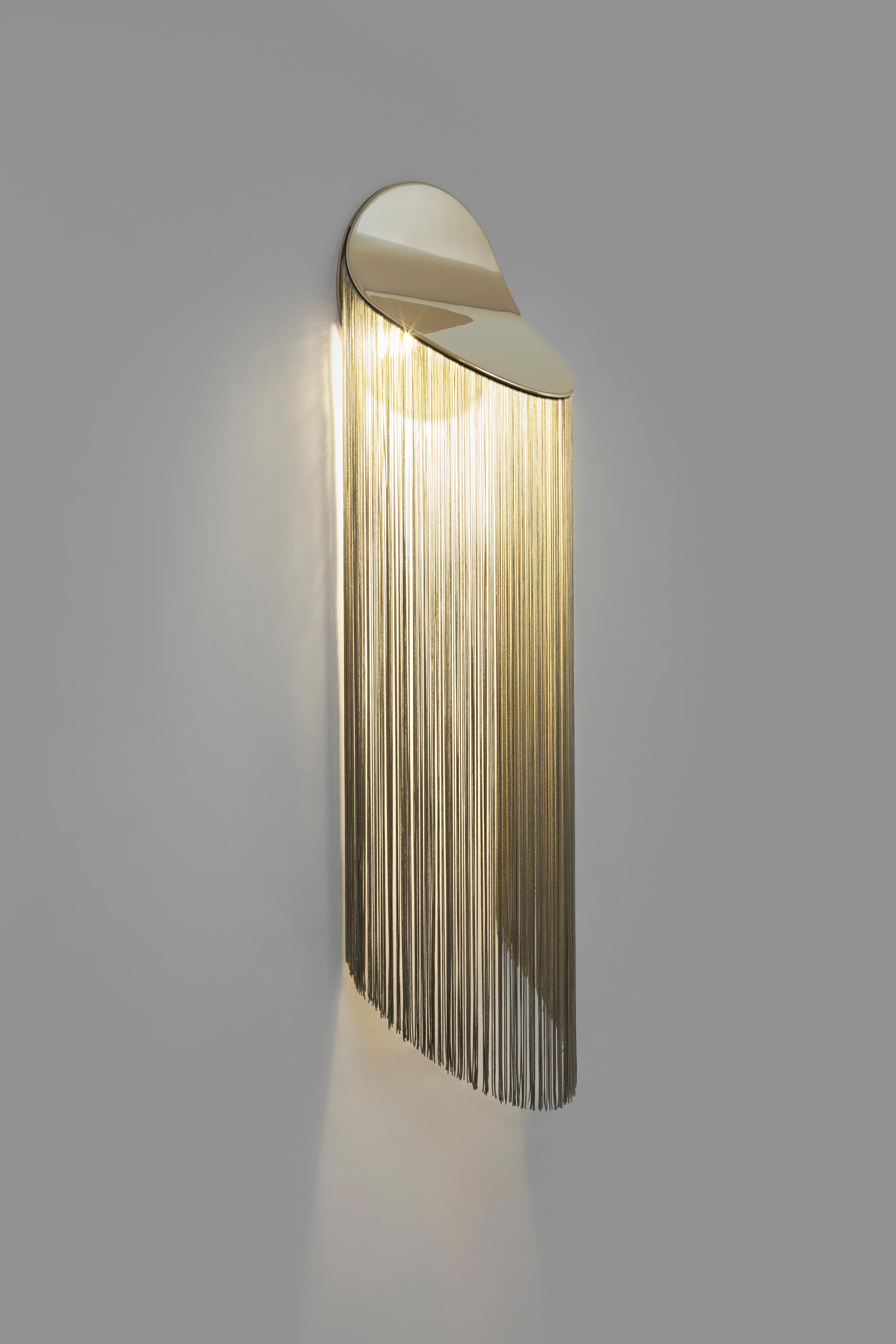 Cé audaciously blends fringes and solid bronze revealing a well-rounded wall-mounted fixture. The unique movement of the fringes brings a fluid effect, distinguishing this piece from previous collections, all the while remaining faithful to the
