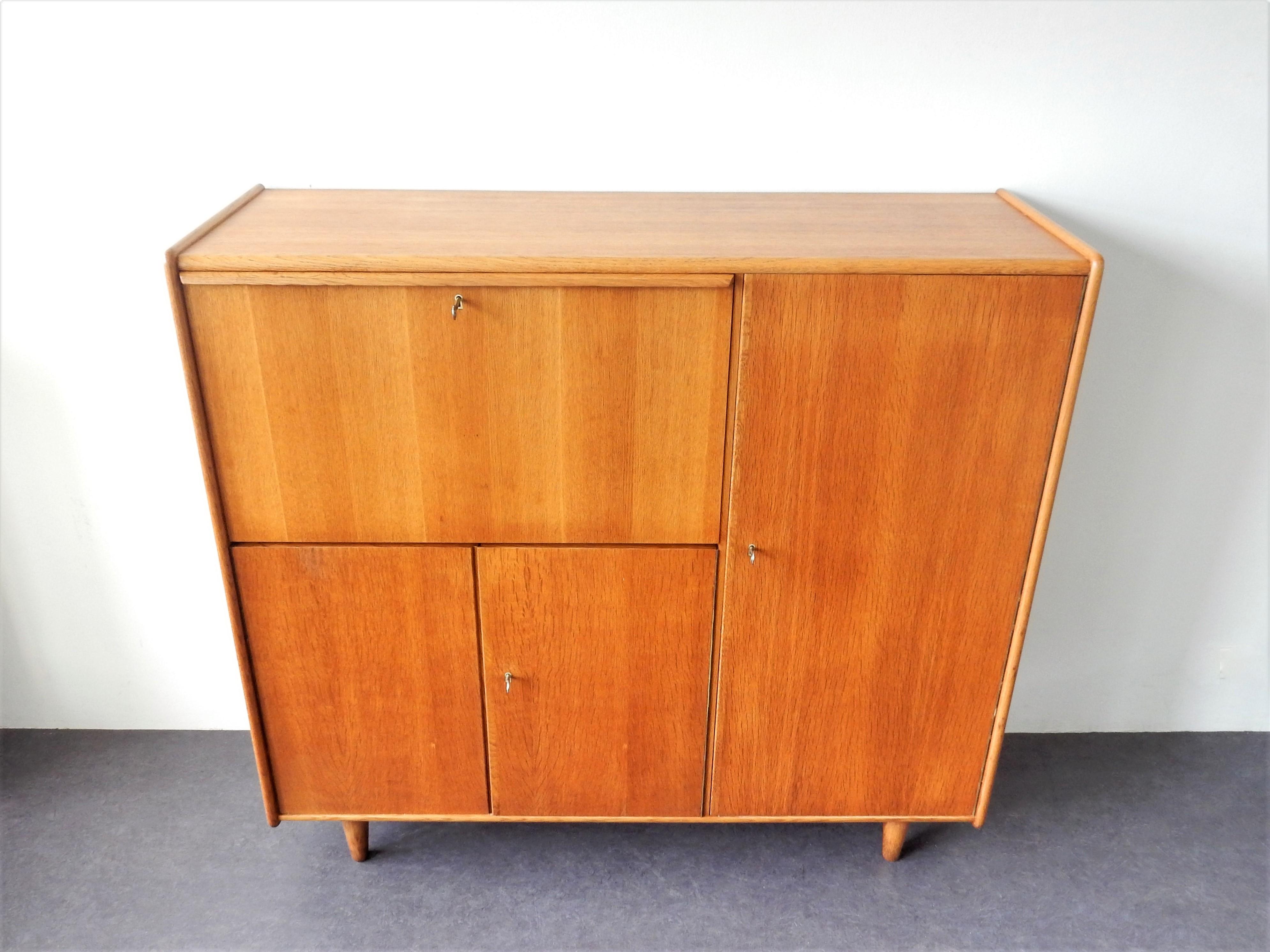 This stunning highboard, model CE09, was designed by Cees Braakman for Pastoe in about 1948. An early design, made of oak veneered board. It has 3 doors and a flap door with 3 keys, of which 2 are original and a third key is a replacement. There is