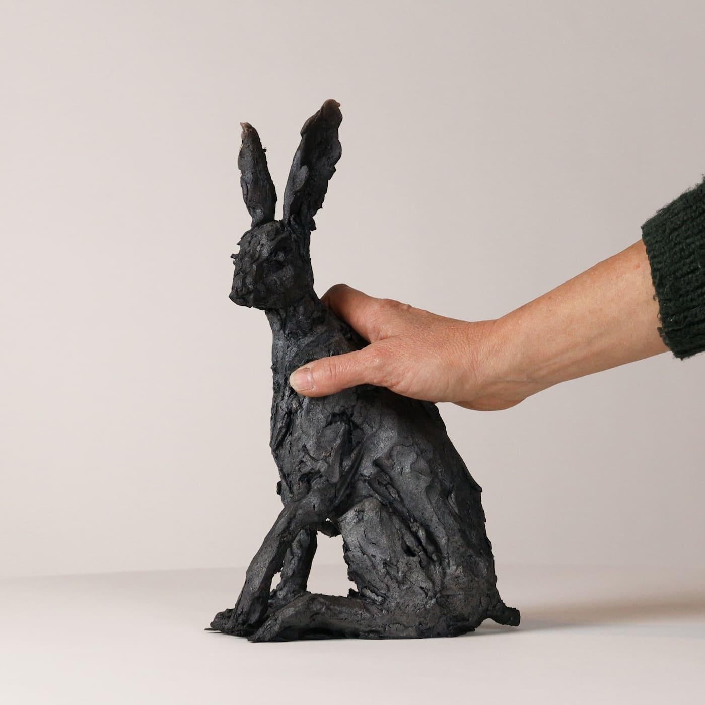 Le lièvre assis est une sculpture unique en grès enfumé de l'artiste contemporaine française Cécile Raynal. Ses dimensions sont de 32,5 × 20 × 10 cm (12,8 × 7,9 × 3,9 in). 

Cette œuvre d'art représente un lièvre vigilant et actif. Cependant,