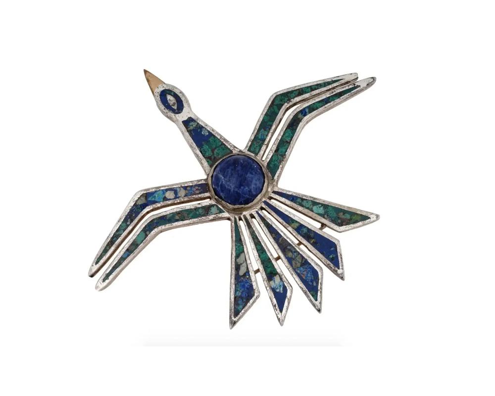 A vintage Mexican modernist 925 Sterling Silver figural jewelry brooch designed by Cecilia Tono. The brooch is made in the shape of a bird, inlaid with various semi precious stones, and encrusted with a large blue stone to the center. Marked with a