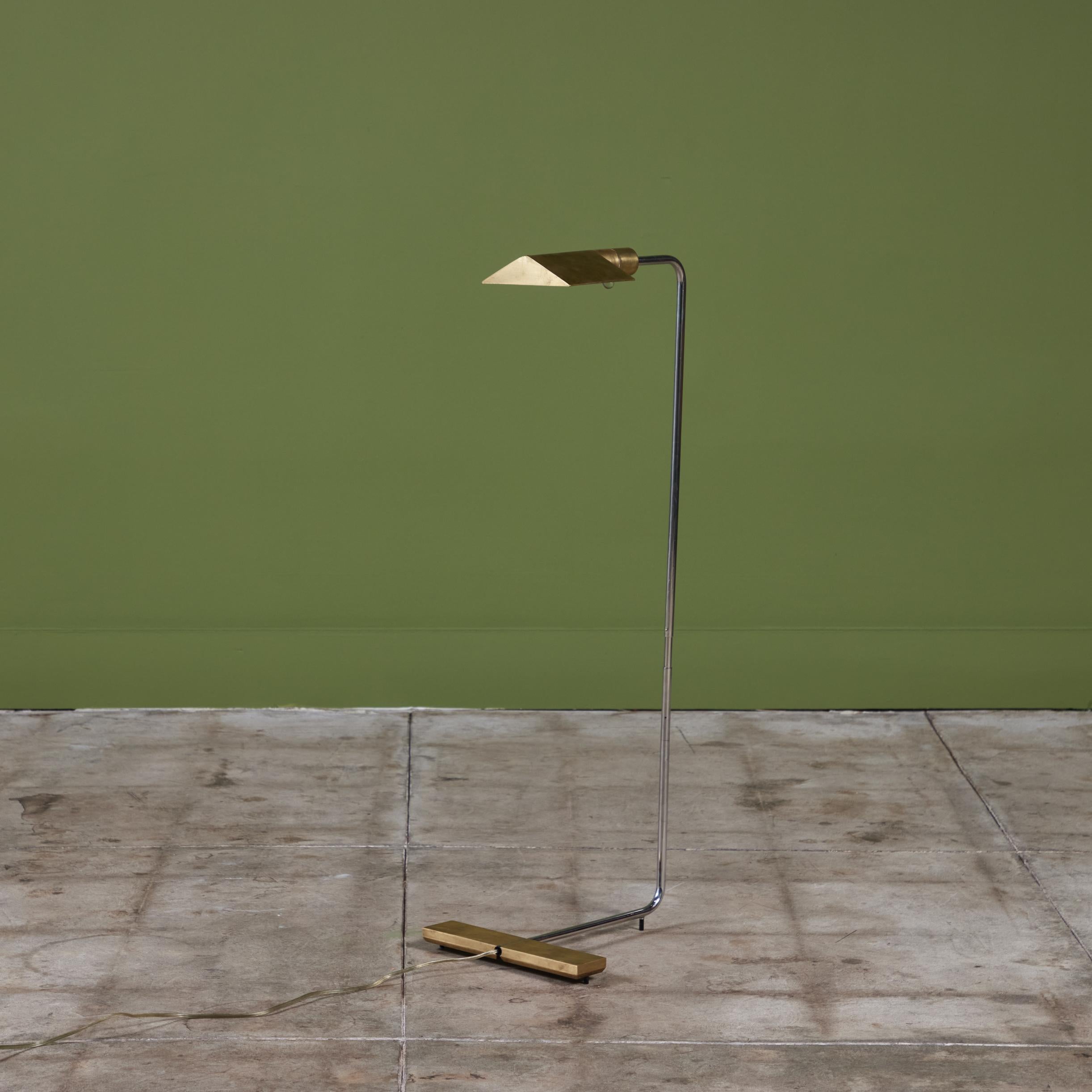 Designed in the 1970s, this brass and stainless steel floor lamp by Cedric Hartman is an enduring design classic. The modernist floor lamp features a triangular brass shade attached to a curved stainless steel stem that offer focused task lighting.