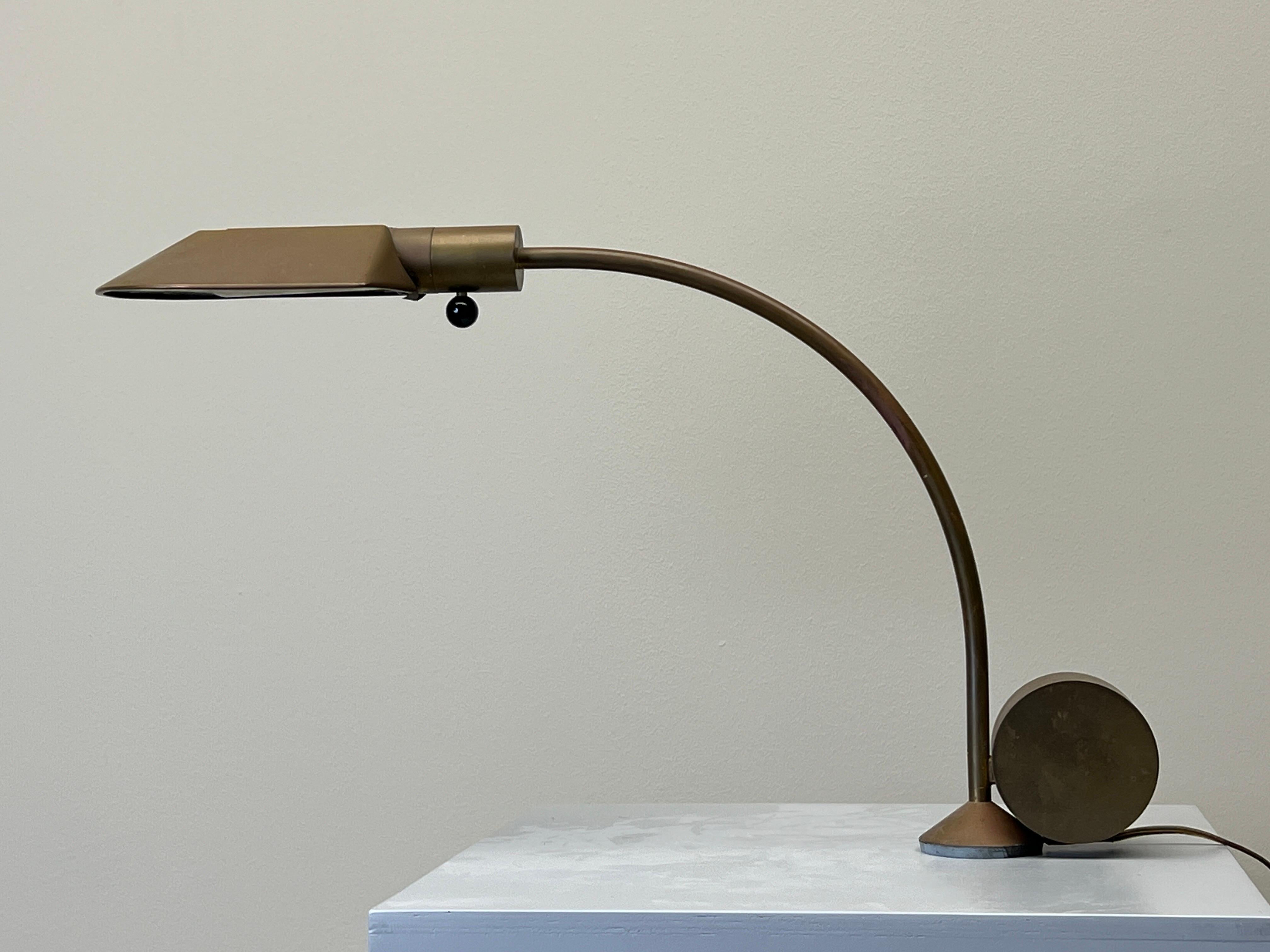 A patinated brass desk lamp with pivoting hood and rotating base designed by Cedric Hartman. 