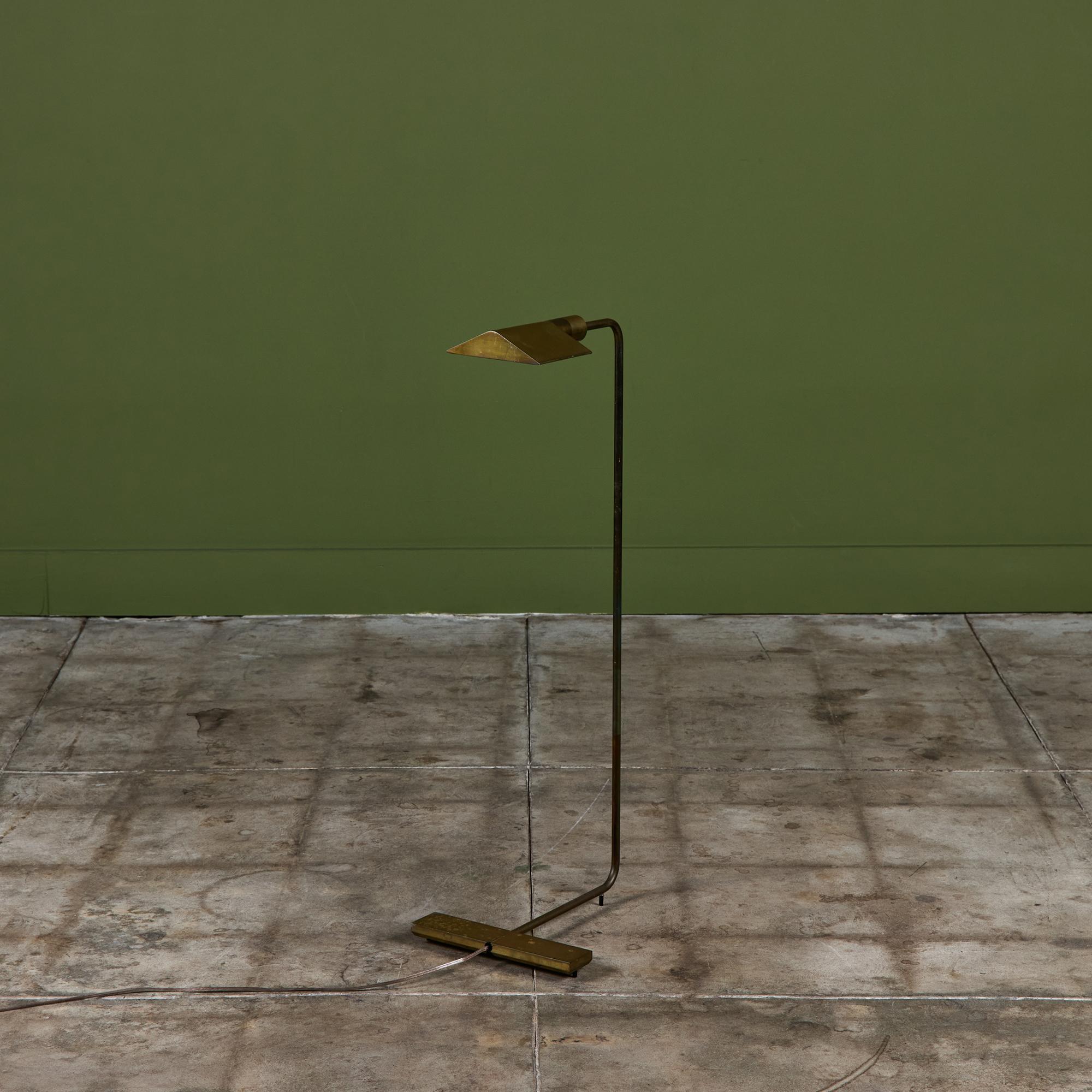 Designed in the 1970s, this brass floor lamp by Cedric Hartman is an enduring design classic. The modernist floor lamp features a triangular brass shade attached to a curved brass stem that offer focused task lighting. The arched pole terminates