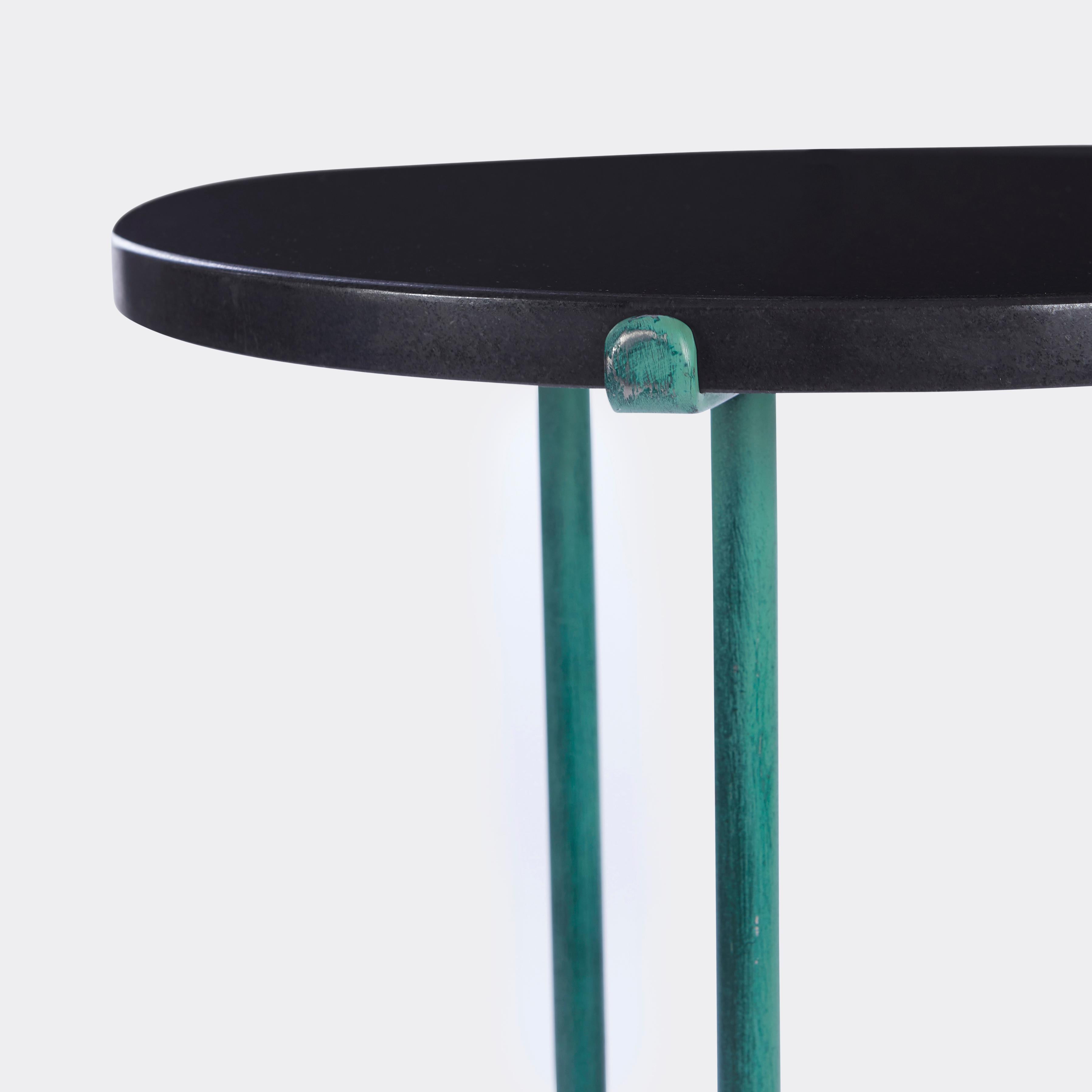 A verdigris painted side table of classical form with black granite top secured by three legs designed in the style of Cedric Hartman (1929-). Circa 1978.