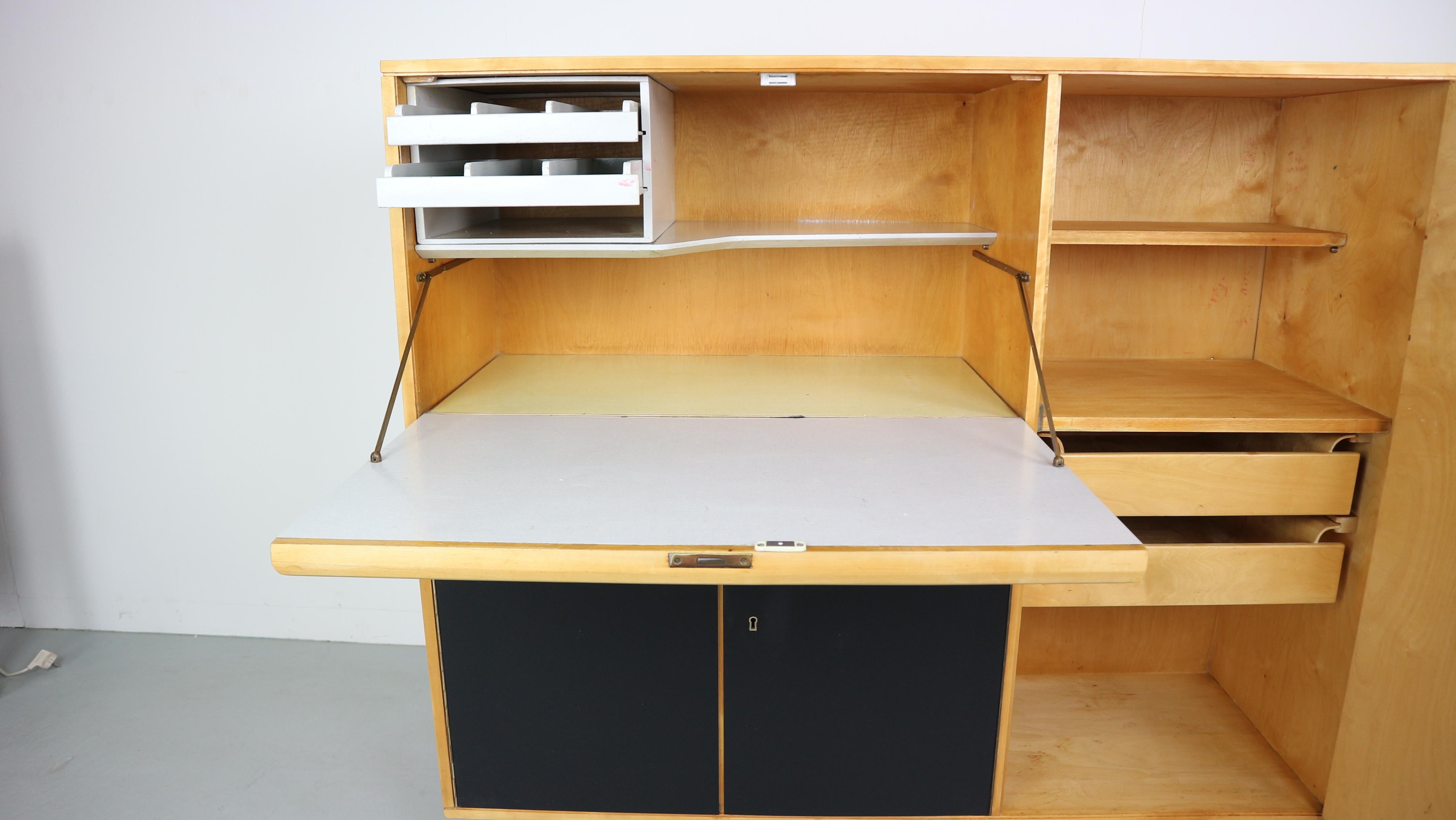 Cabinet CB01 with desk and storage place made of birch wood, designed by Cees Braakman for UMS Pastoe, circa 1950. Desk with grey shelve. At the right side door with shelve and two drawers inside, underneath the desk compartment with shelve inside.