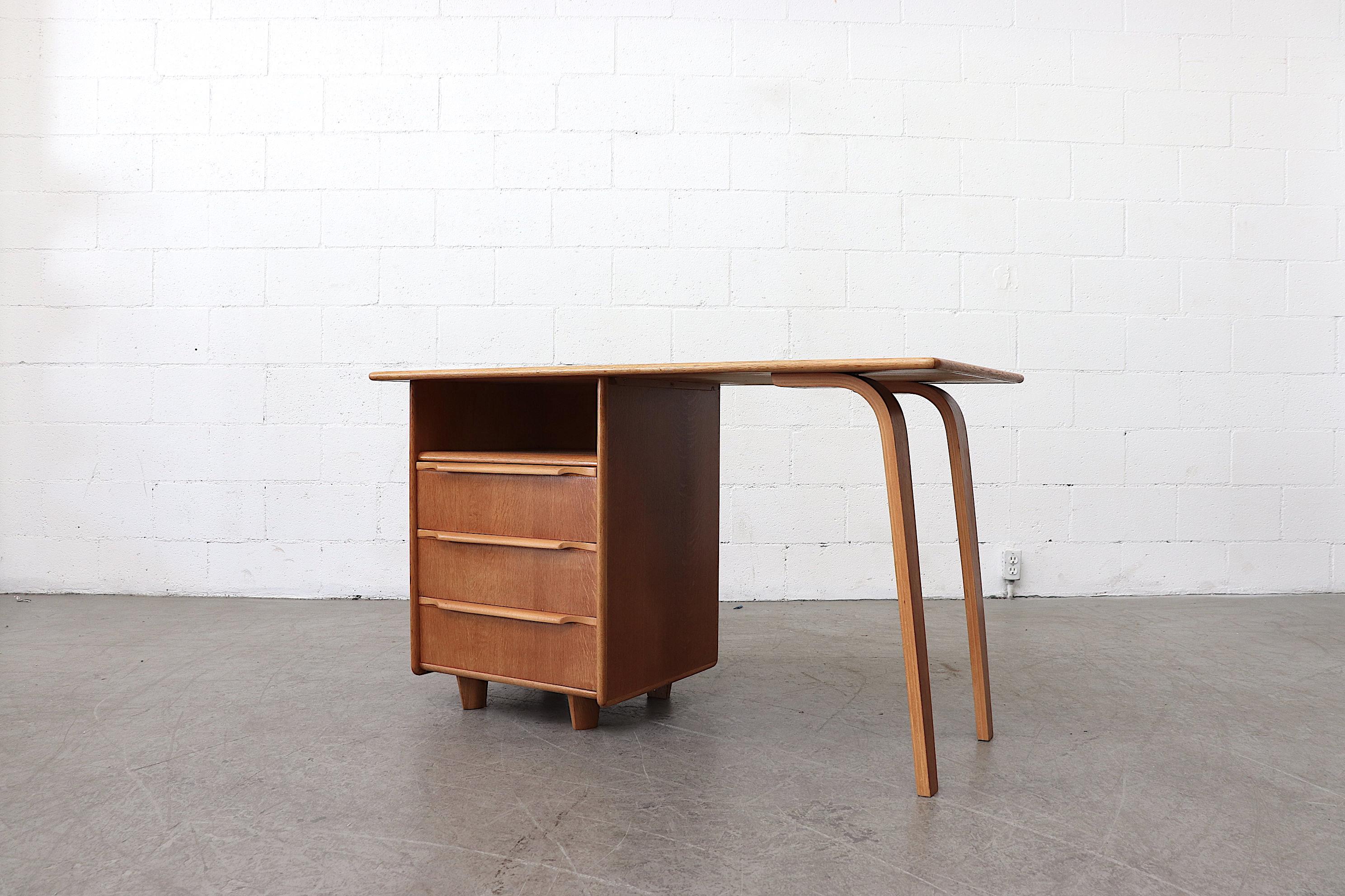 Sweet little desk designed in 1948 by Cees Braakman from the oak series for Pastoe, handsome bent legs. 3 left-side sliding drawers with organically carved hand pulls. Desk in original condition.