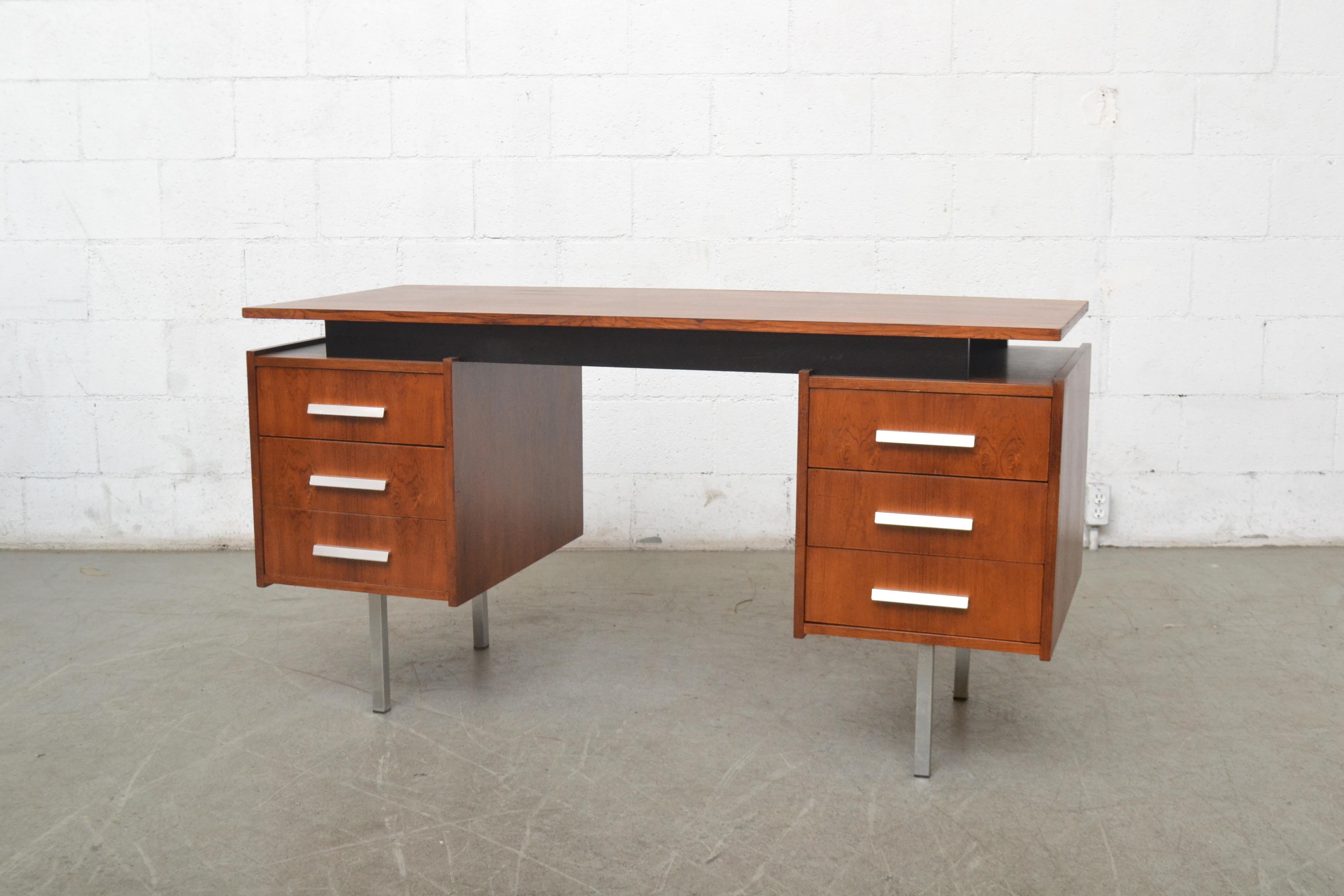 Midcentury office desk designed by Cees Braakman for Pastoe. Lightly refinished teak. Floating top with black painted wood riser. Three sliding drawers on each side with aluminum pulls and chrome legs.