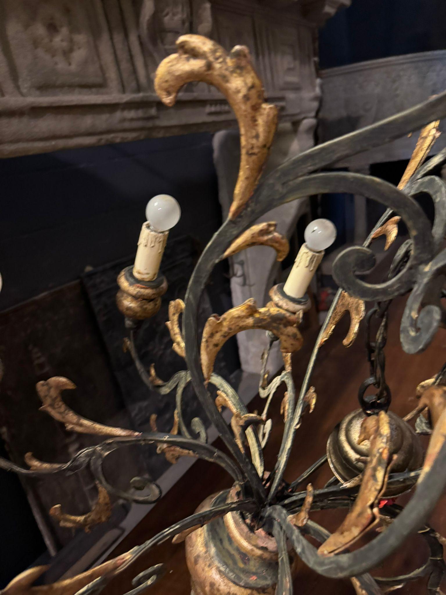 Antique ceiling chandelier, with 8 arms and lights, decorated and carved from sheet metal with a gilded wooden lamp holder, bottle green and gold colors. The wiring needs to be checked. Original from the late 19th century and originating in