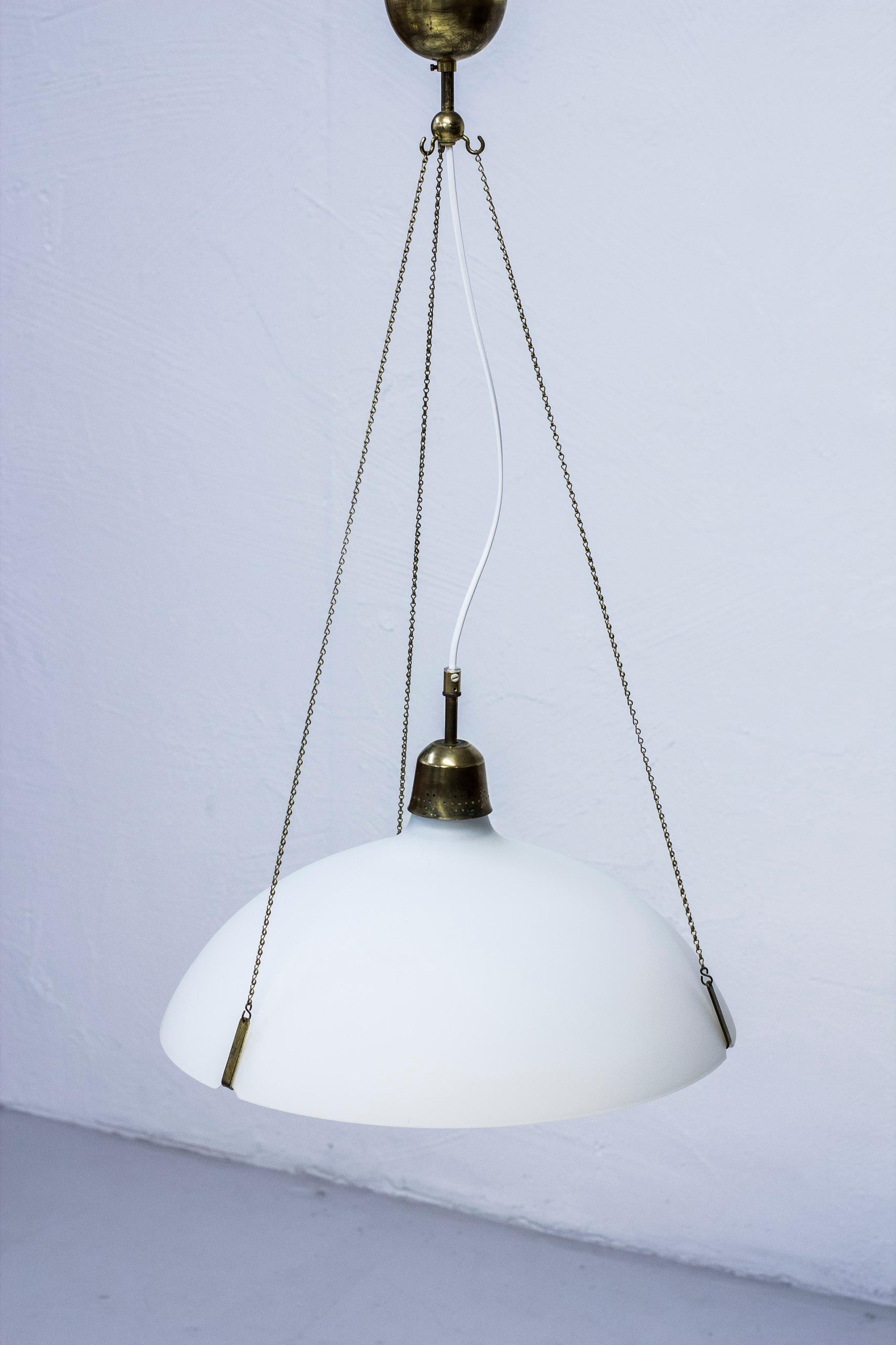 Ceiling lamp attributed to Bertil Brisborg. Produced by Nordiska Kompaniet in Sweden during the 1950s. Made from opaline glass and brass. Possible to extend the lamp to ca 150 cm in height or more on request. Very good condition with few signs of