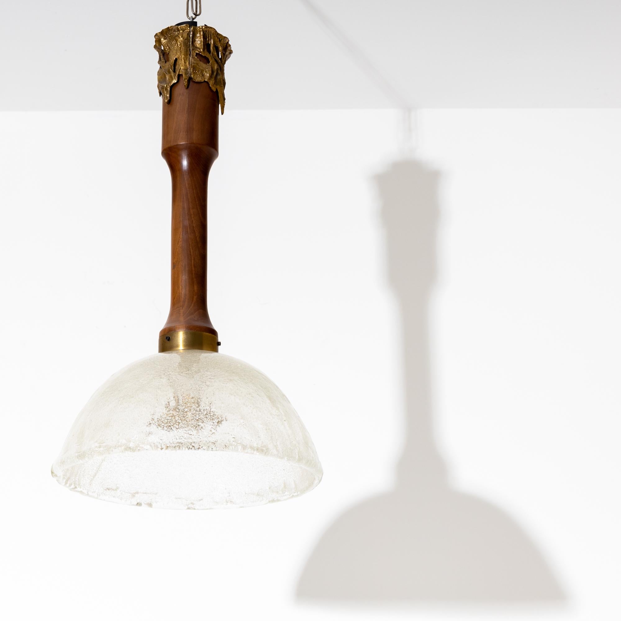Ceiling lamp with glass shade and wooden shaft. The upper end is surrounded by an irregular bronze relief, signed 