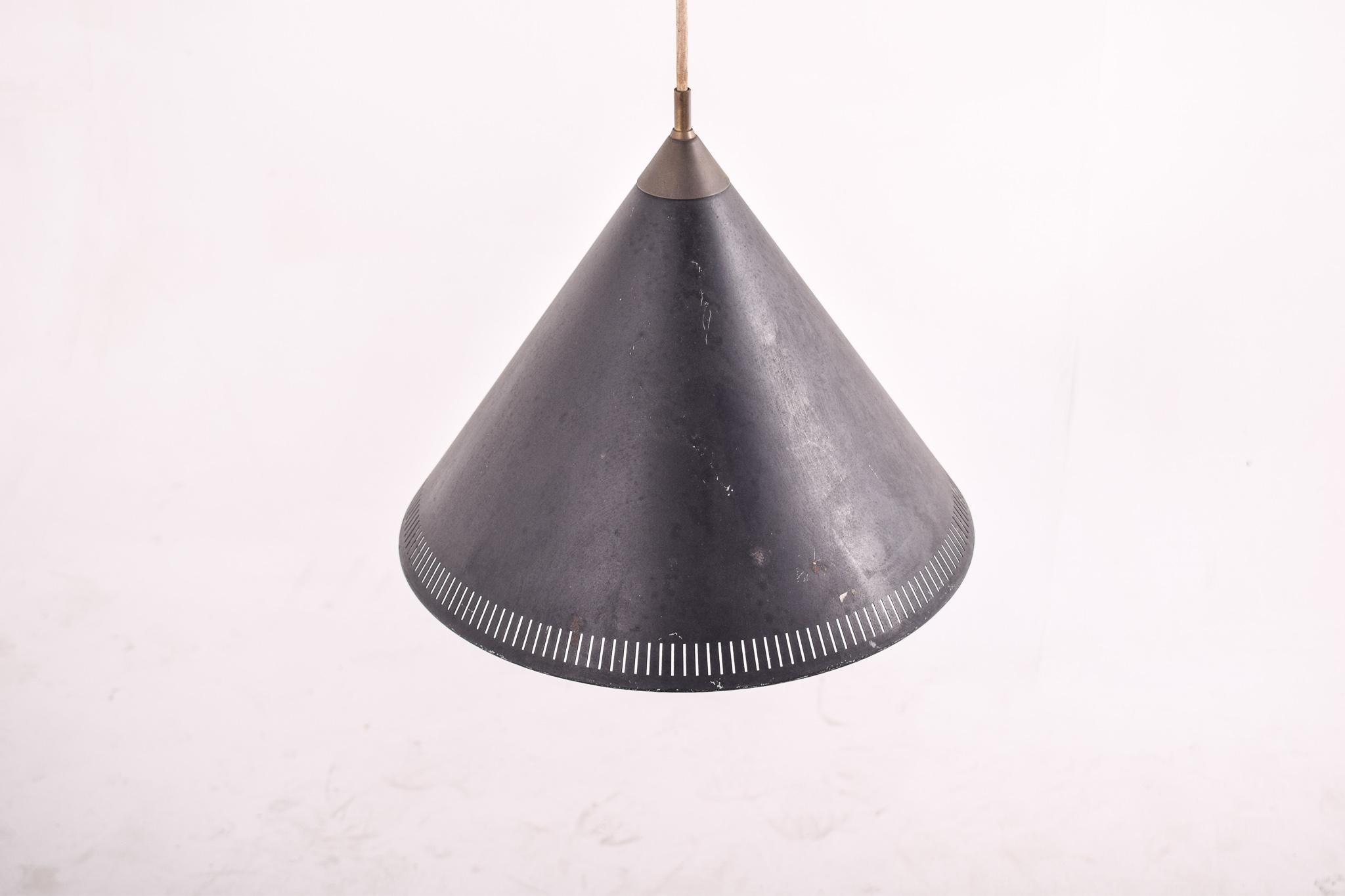 Black cone-shaped light pendant by Bent Karlby for Lyfa. Lyfa stands behind this beauty, which was designed in the 1960s. The cone-shaped design of the lamp gives a very good light. It features perforated metal to allow it to shine beams of light.