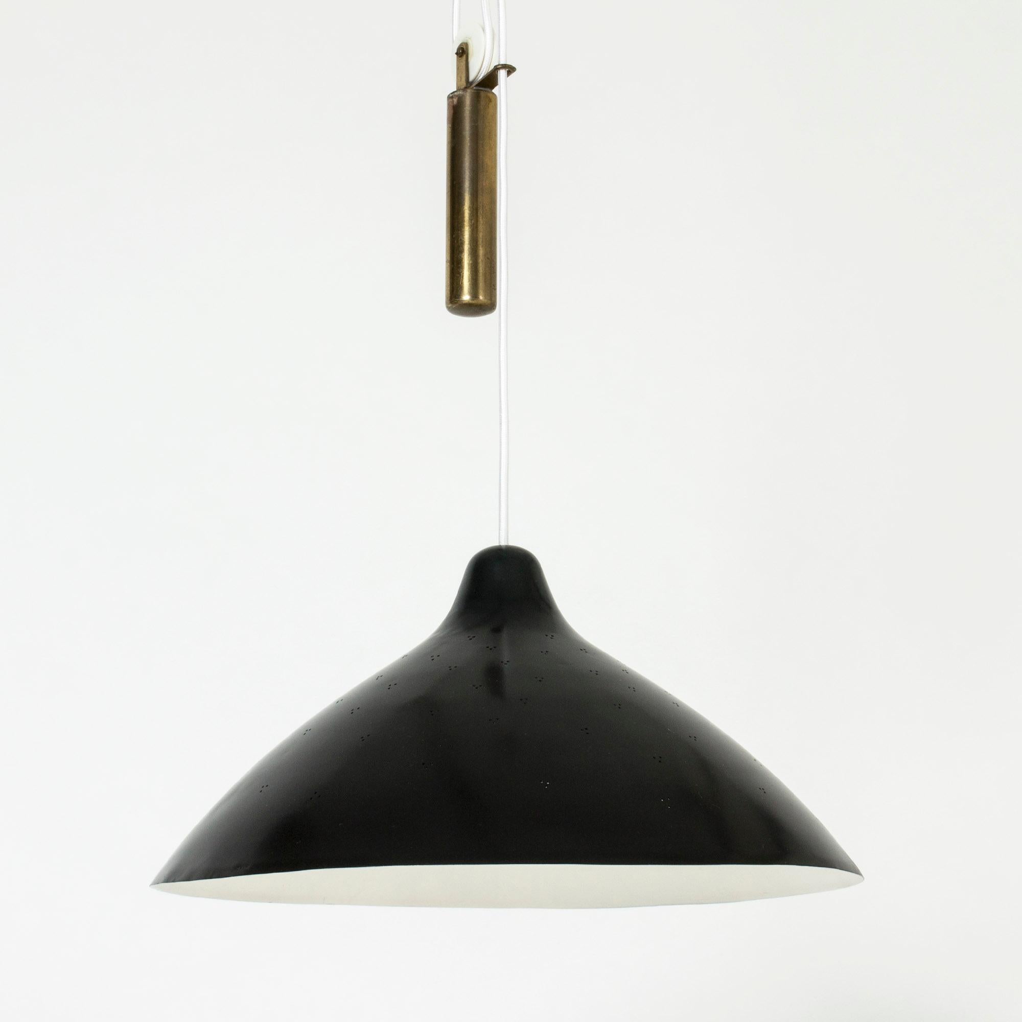 Elegant ceiling lamp by Lisa Johansson-Pape, made from brass with a black lacquered shade. Small perforated holes create a beautiful, subtle effect. A brass weight allows the height to be easily adjusted and makes a decorative detail.