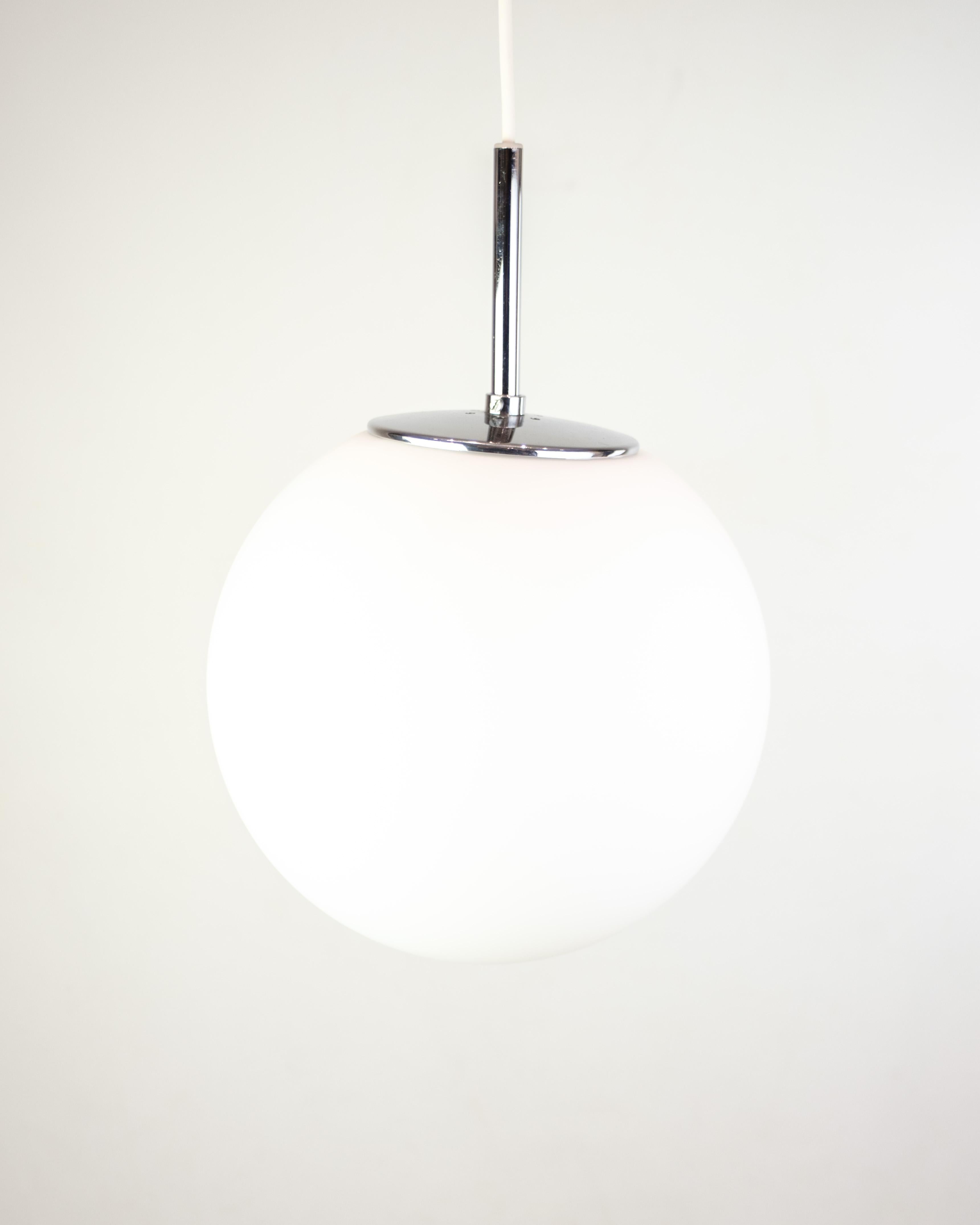 Colgante de cristal esmerilado esférico con suspensión cromada y cable blanco. La lámpara da una luz suave y difusa y encaja perfectamente encima de una mesa de comedor o en un recibidor. Una pieza minimalista de diseño escandinavo, donde la función
