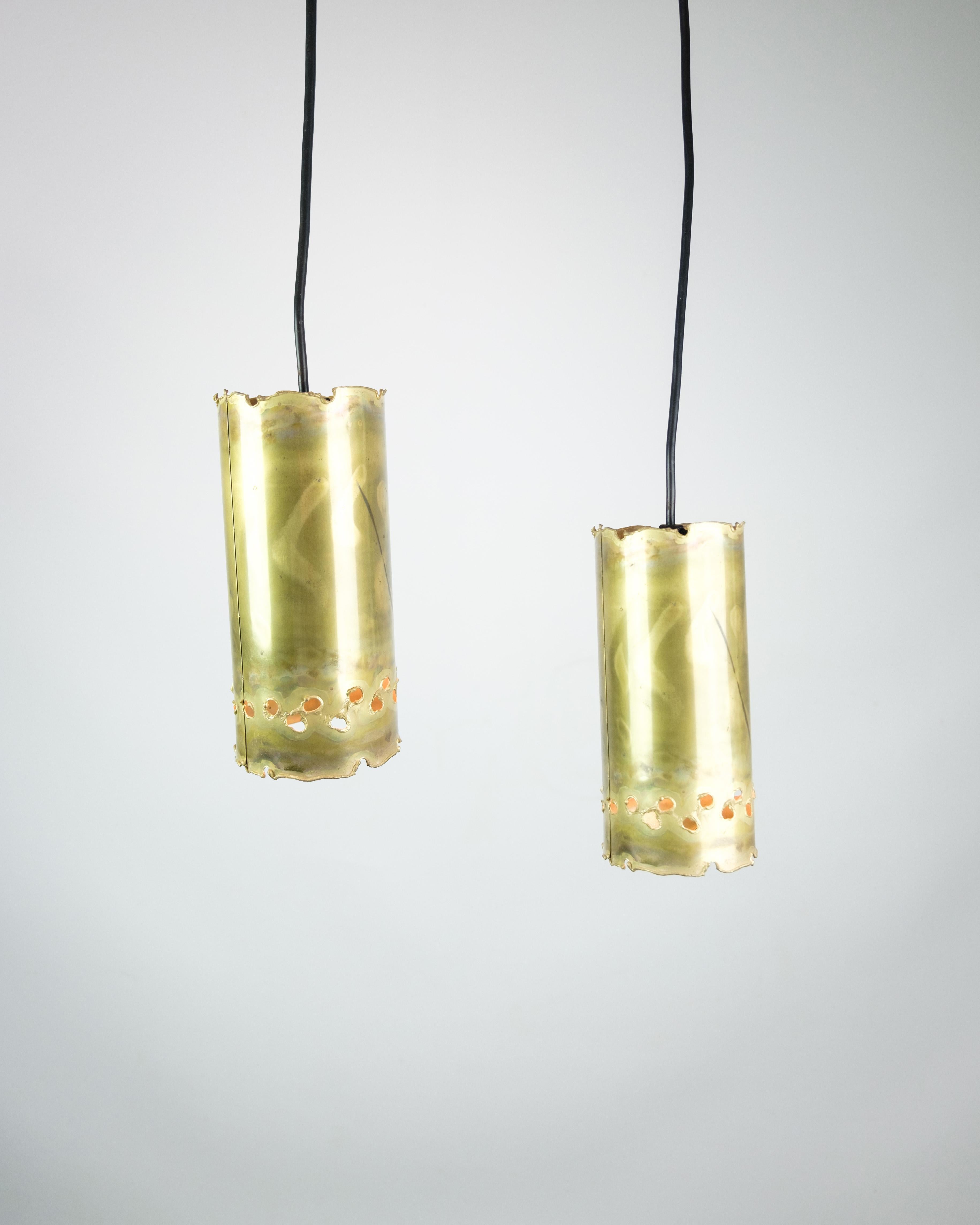 The brass ceiling lamp, characterized by a characteristic cylinder shape and a black cord, is a remarkable example of lighting design from the 1960s, created by the talented designer Sven Aage Holm Sørensen. This iconic piece captures the spirit of