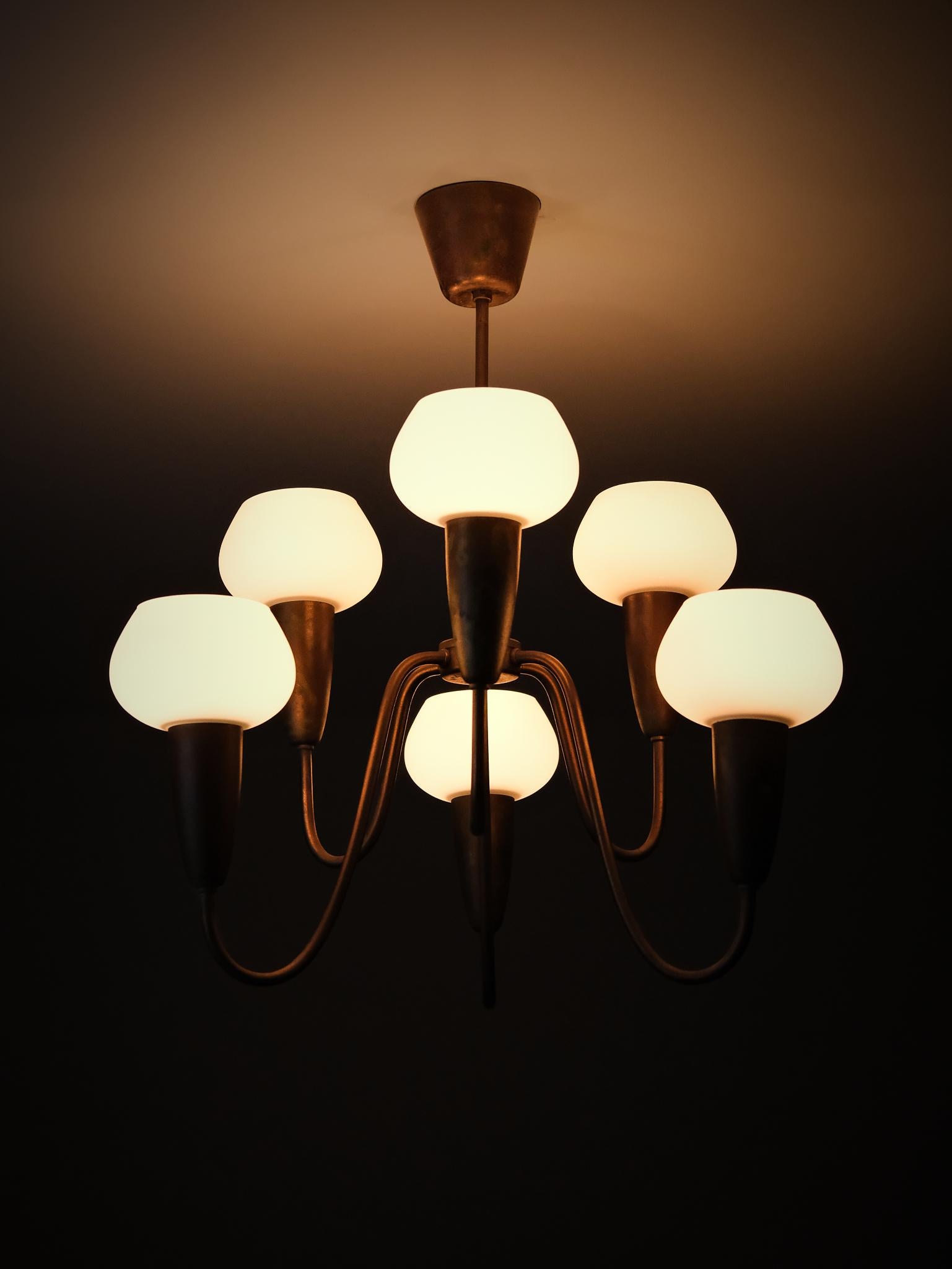 Ein zeitloses skandinavisches Designstück aus den 1950er Jahren, hergestellt von Arvid Böhlmarks Lampfabrik. Diese elegante Deckenleuchte hat einen Messingrahmen mit schön geschwungenen Armen und sechs Opalglasschirmen, die ein weiches und