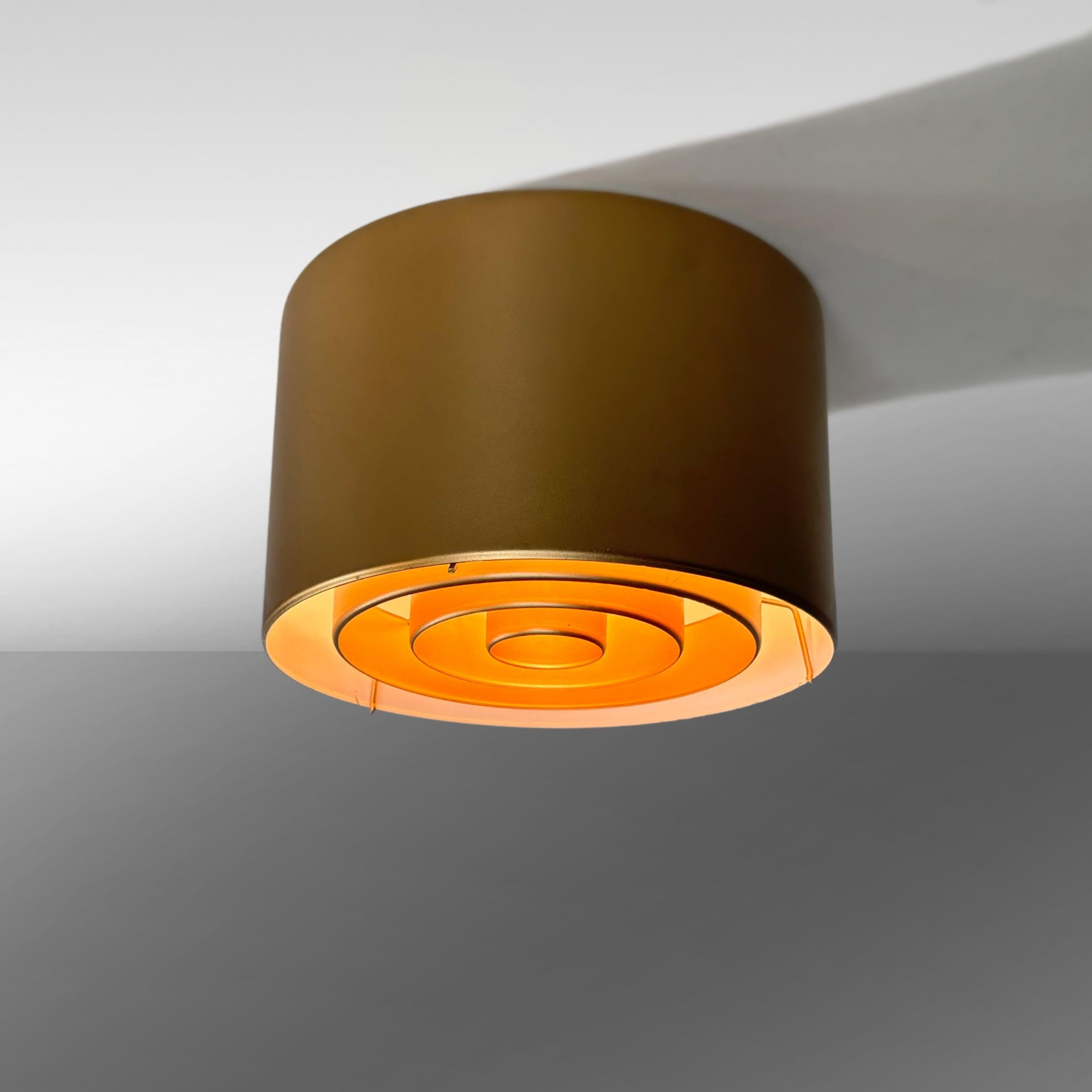 Plafoniera in metallo bronzato, modello 971-135/20, di Yki Nummi per il produttore finlandese Orno. Presenta un design minimalista con una struttura cilindrica e un diffusore in metallo rimovibile. Etichetta del produttore all'interno.