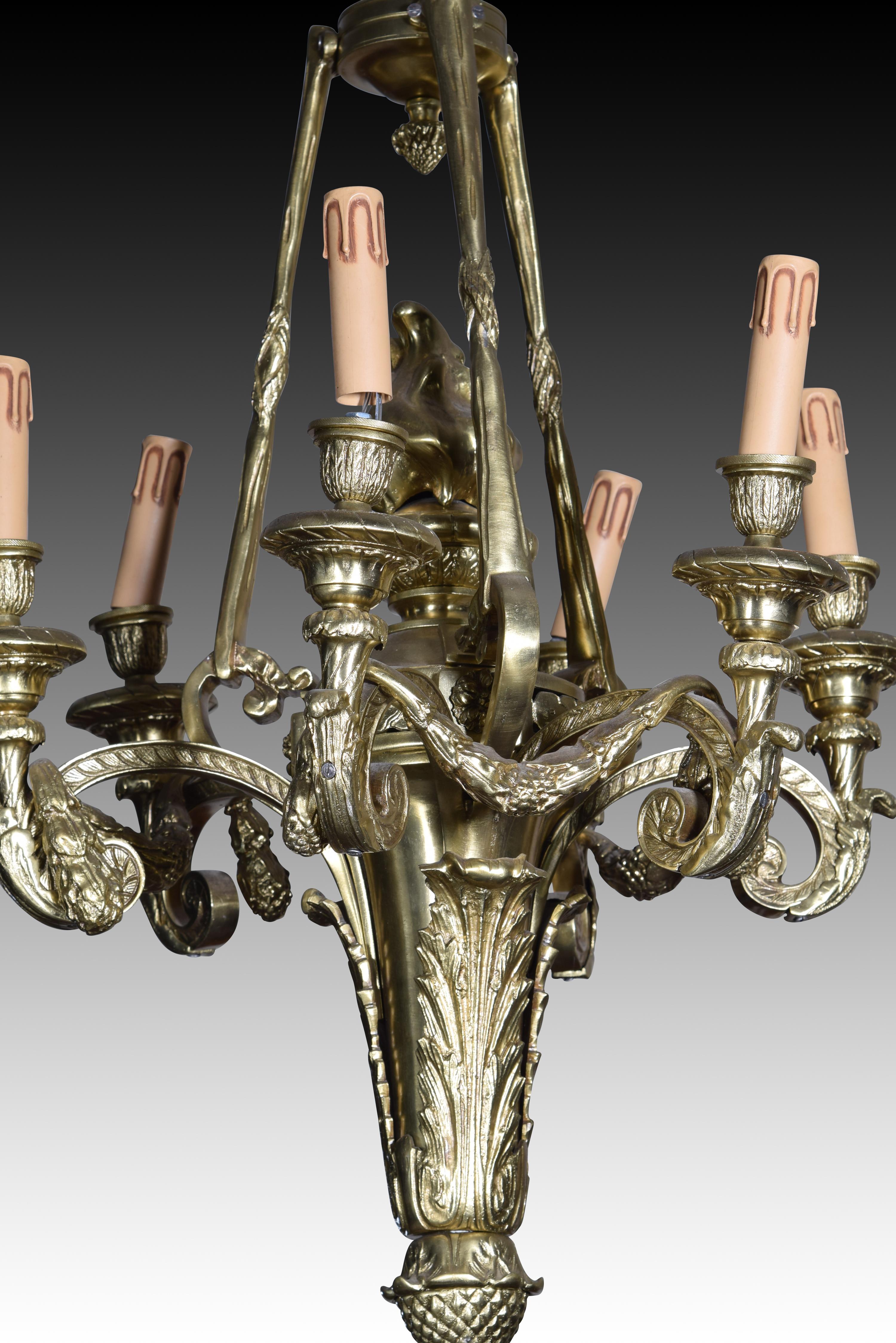 Ceiling light. Bronze. 
Six-light ceiling lamp with curved arms decorated with architectural and plant elements that start from a torch, attached to the ceiling piece by chains. Both in the decorative elements and in the shape you can see a direct