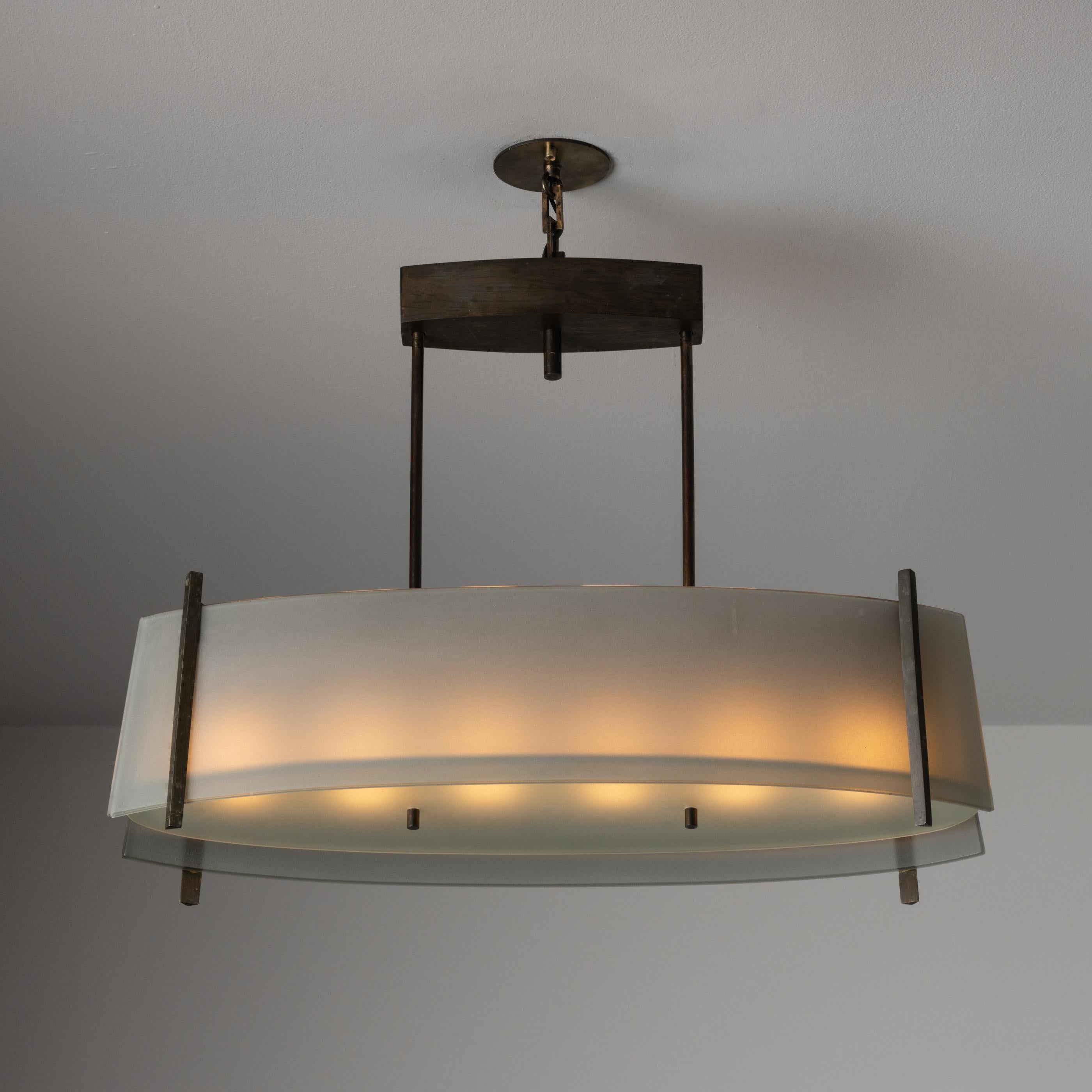 Suspension light by Fontana Arte. Designed and Manufactured in Italy, circa the 1950s. Clear sandblasted glass shade with aged brass framing. Suspended by a brass chain and custom canopy. Holds six E14 sockets. Bulbs recommended consist of six E14