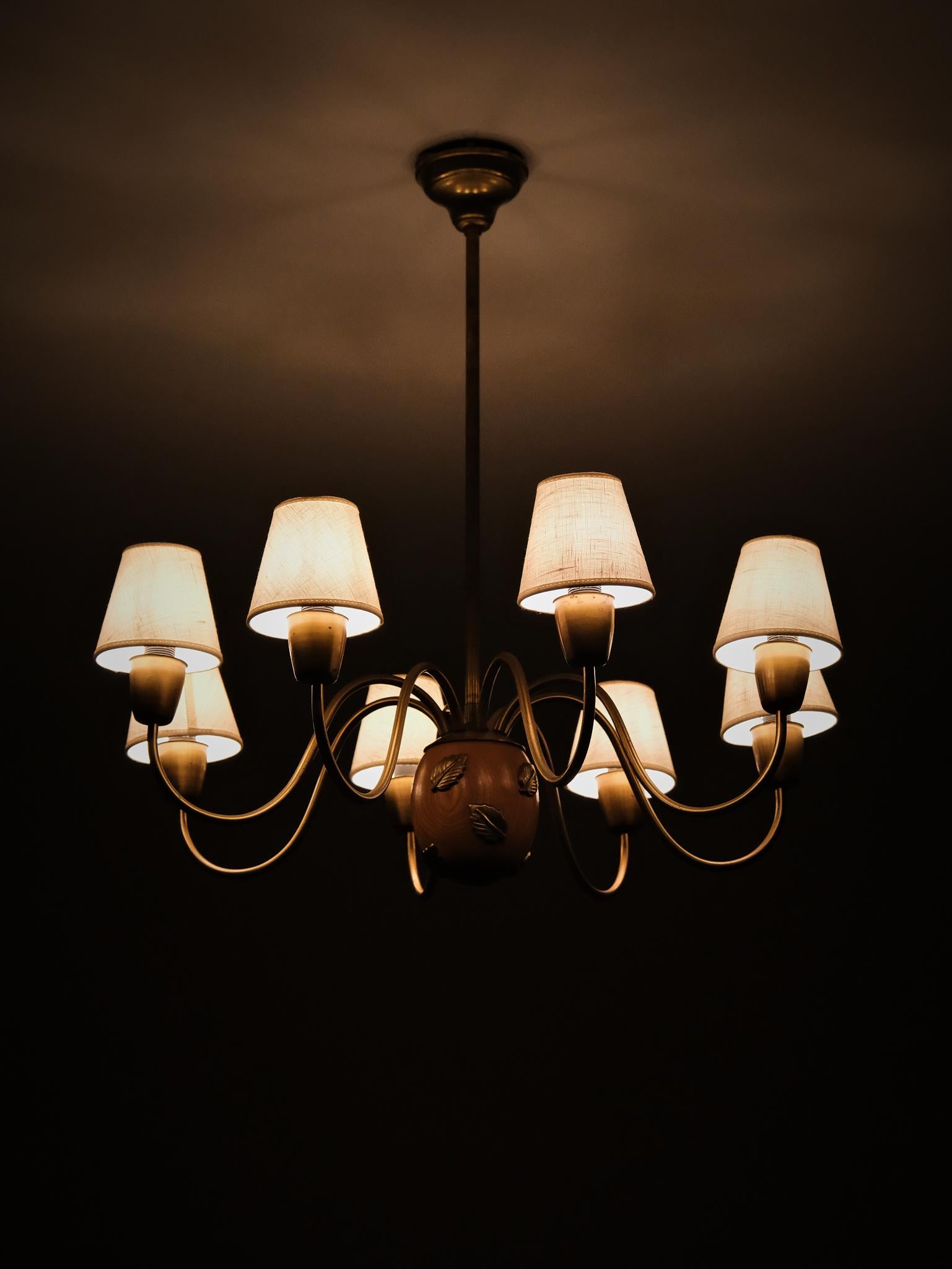 Elegant eight-armed chandelier designed by Hans Bergström and produced by Ateljé Lyktan in the 1940s. 

Executed in brass with sculptural arms and refined detailing, centered around a mahogany sphere adorned with decorative leaf motifs. A timeless