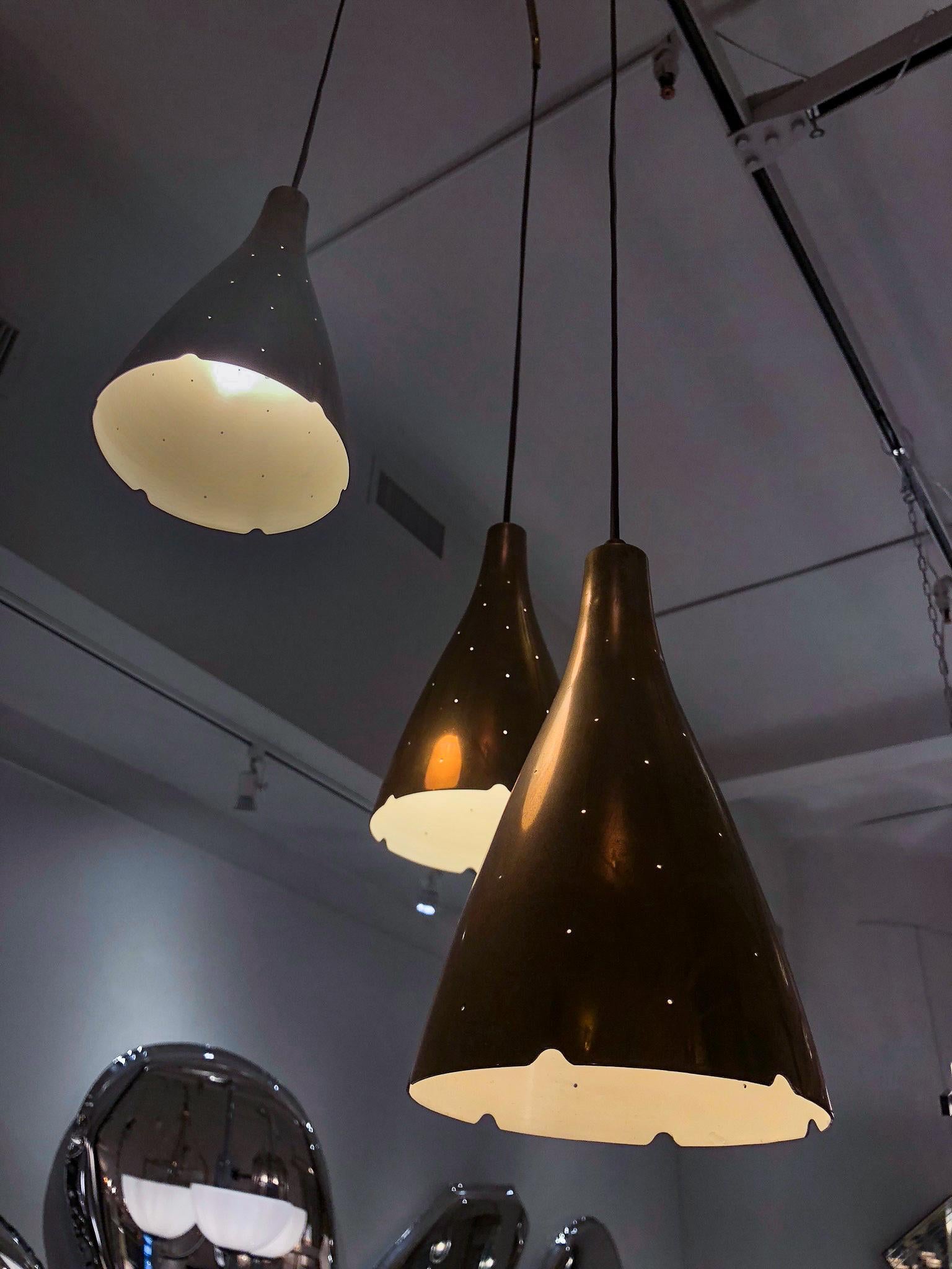 Three perforated and conical brass shades, suspended at different heights from a three-spoke canopy. Designed by Tynell, produced by Taito Oy.
Lantern body: Height 10”.

OUR REFERENCE N6958