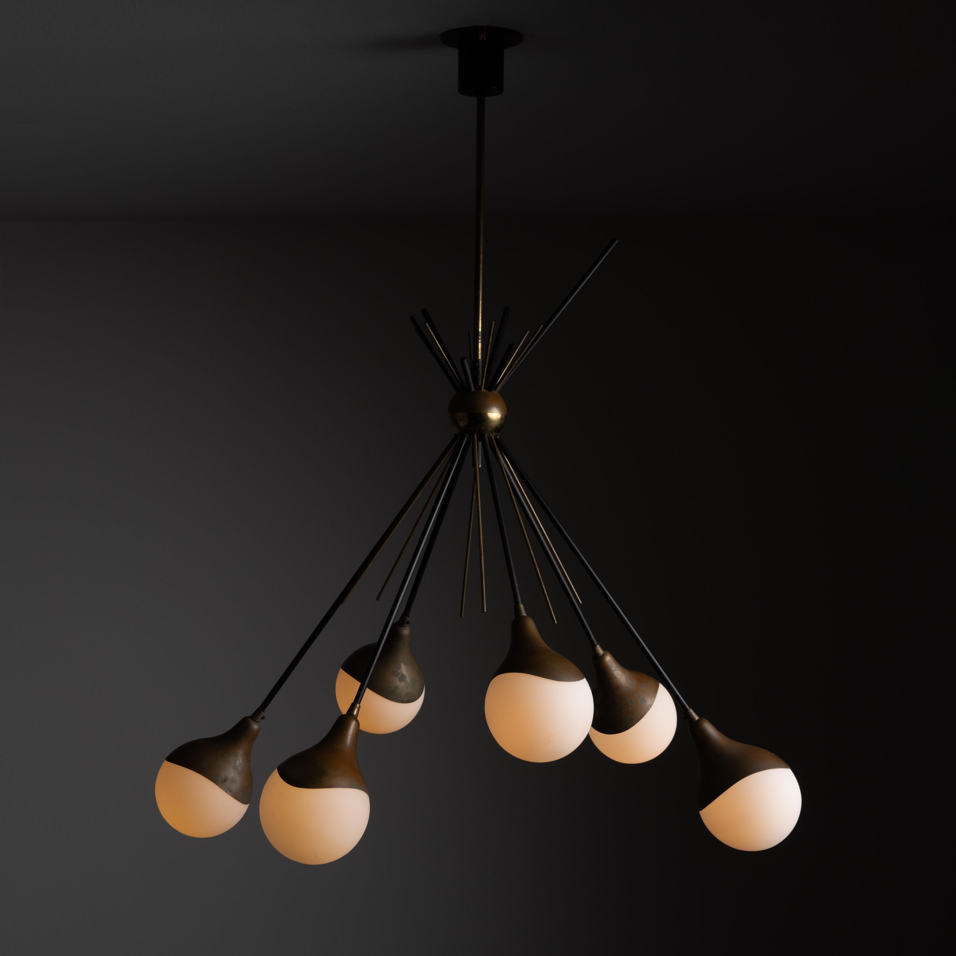 Ceiling Light by Stilnovo. Designed and manufactured in Italy, circa the 1950s. A visually striking chandelier with multi-armed rods darting through a centered brass ball. Each arm ends with a detailed brass cup, holding a sandblasted opal ball.