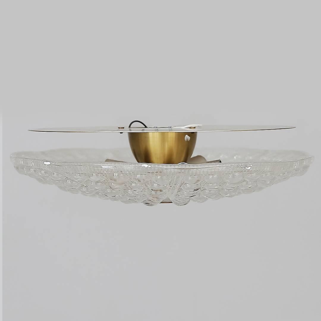 Carl Fagerlund's brass-mounted pressed glass diamond pattern flushmount ceiling fixtures designed for Orrefors of Sweden. The fixture is fitted with six E14 bulbs, brass backplate and round brass mount on top.
Up to three available.