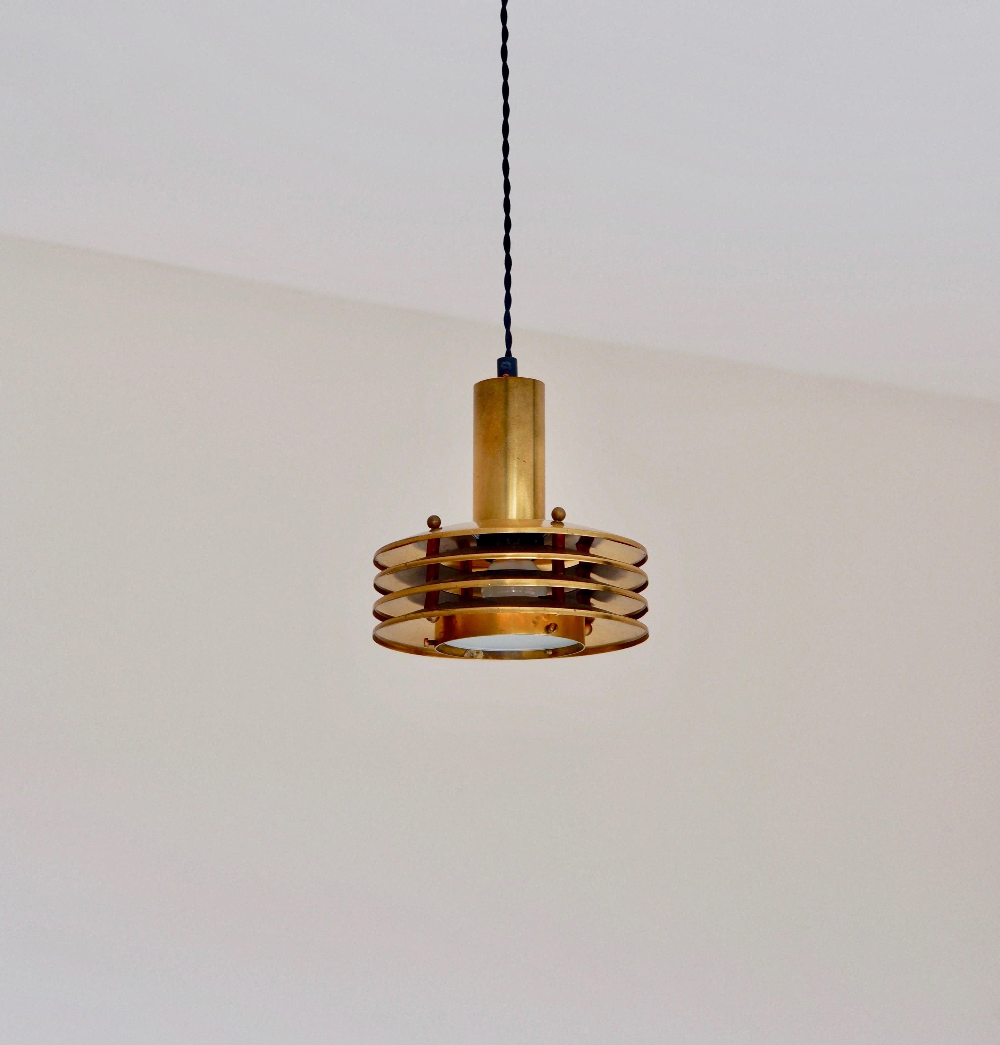 Rare pendanr designed by Kai Ruokonen, made in solid brass with 4 rings and a glass diffuser. The overhall condition is good and the lamp has a good patina with trace of use and age. The lamp is composed by 4 lamp shade rings hold them together by