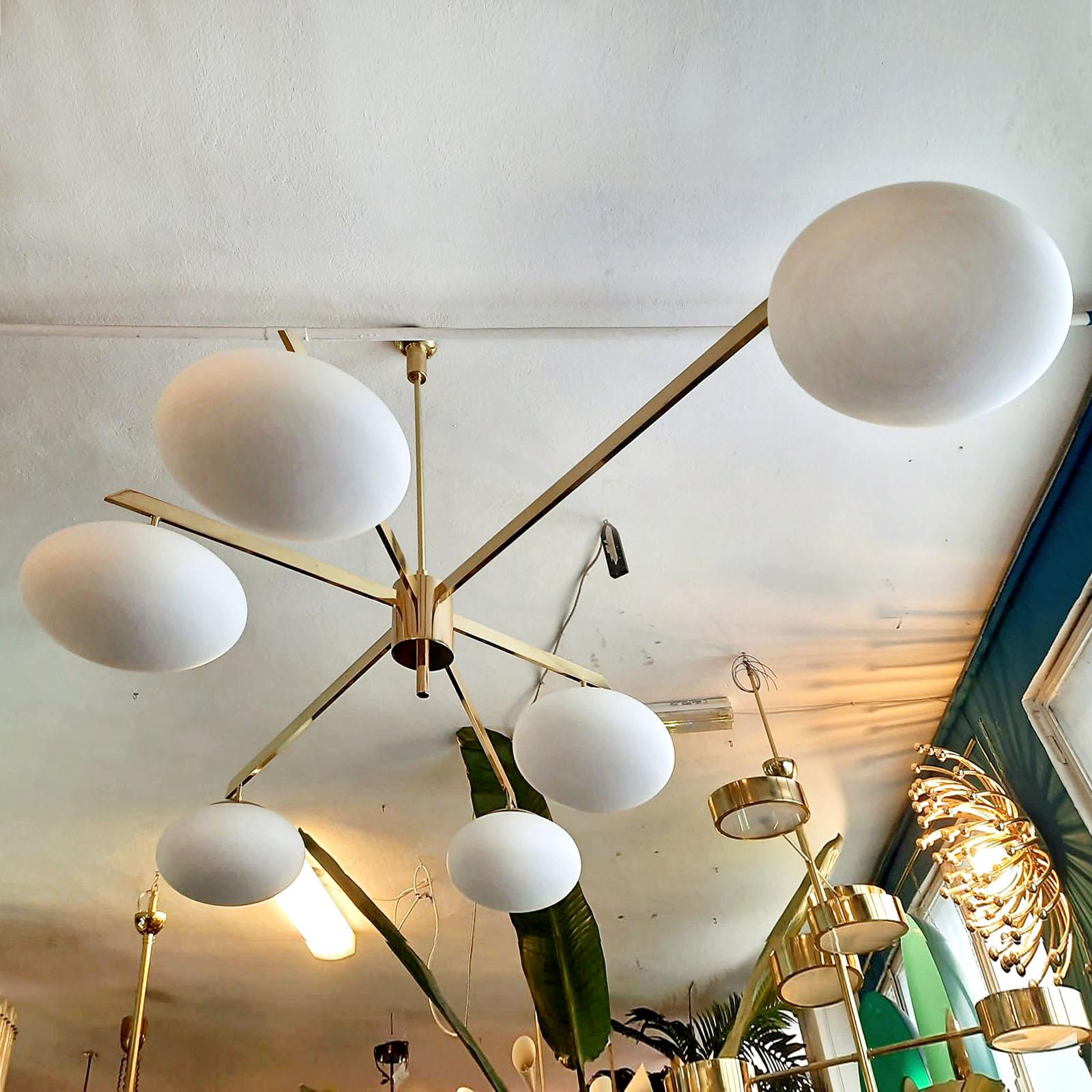 Made after a design by Angelo Lelli, in the mid century Italian style, this beautiful ceiling fixture impress by its lines simplicity and clean design. Made of brass and with opaque glass rounded shades, it throws a strong, yet diffuse light in the