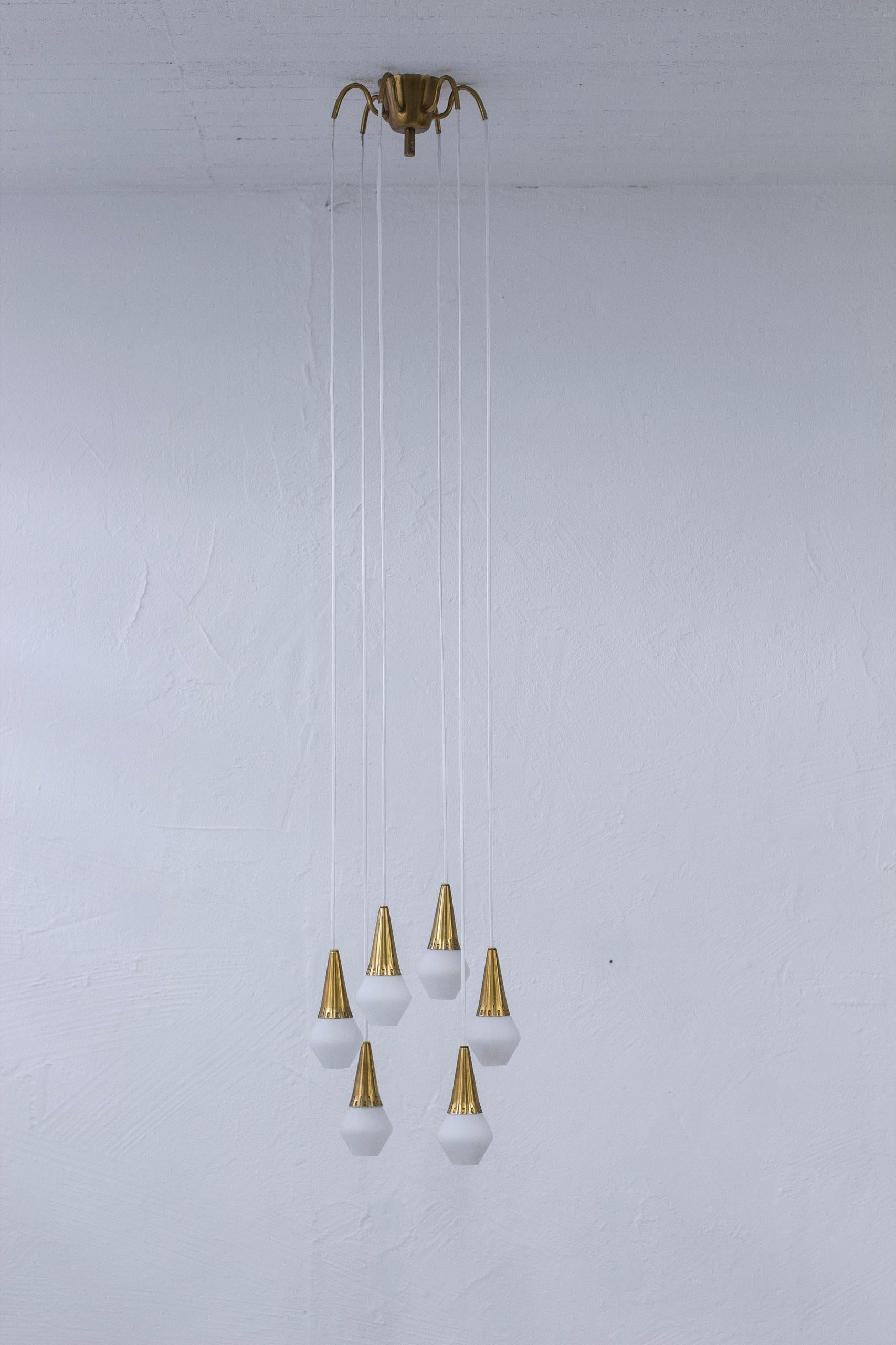 Ceiling pendant lamp designed by Harald Notini. produced in Sweden by Böhlmarks lampfabrik during the 1950s. Six hanging pendants attached to a six armed ceiling mount made from brass. Original glasses in white opaline. Very good vintage condition