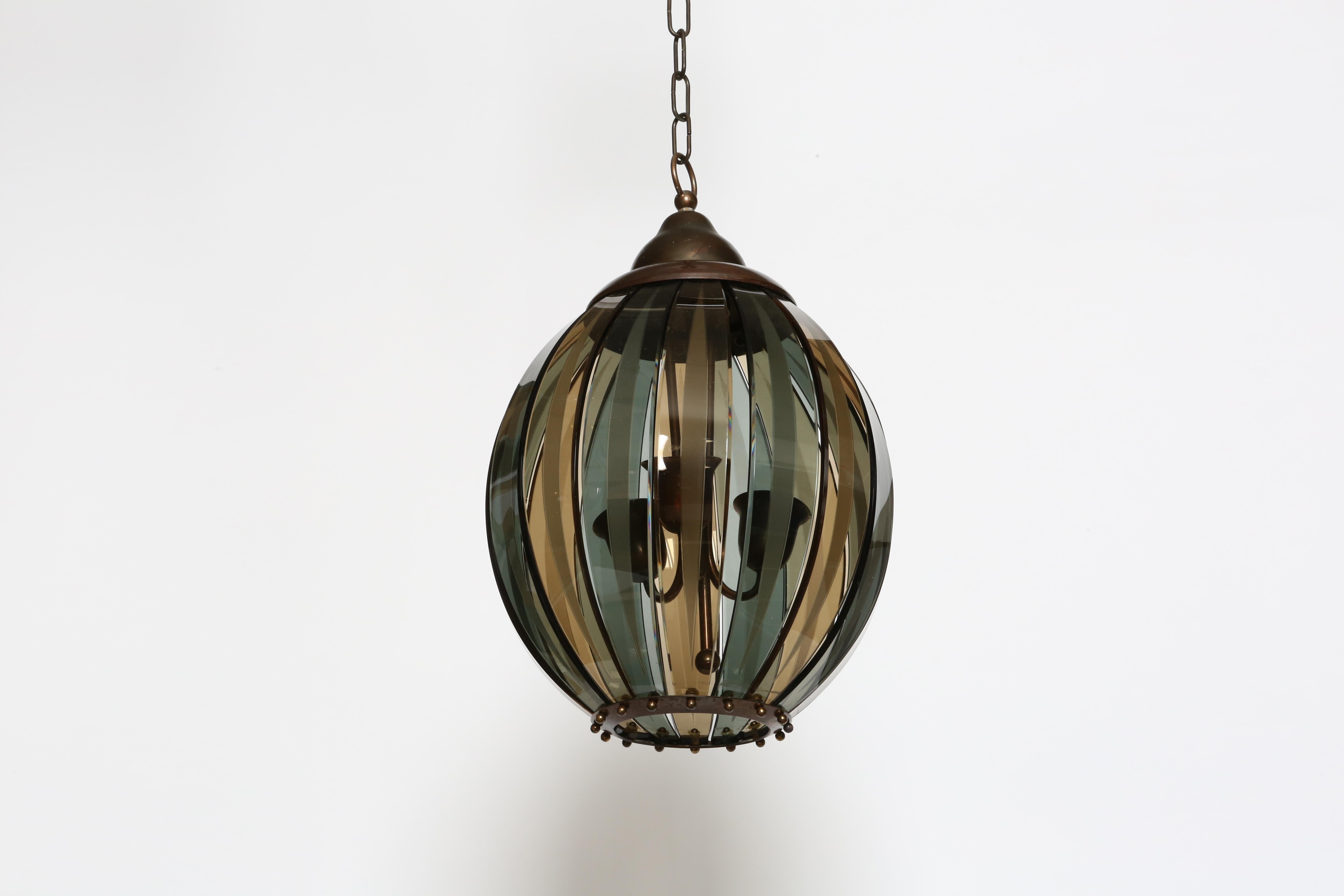 Suspension ceiling light by Stilnovo, attributed.
Designed and manufactured in Italy in 1970s
Smoked colored glass in 2 tones, patinated brass frame.
Height adjustable.
Light's body is 20.5 inches.
Three candelabra sockets.
Complimentary US rewiring