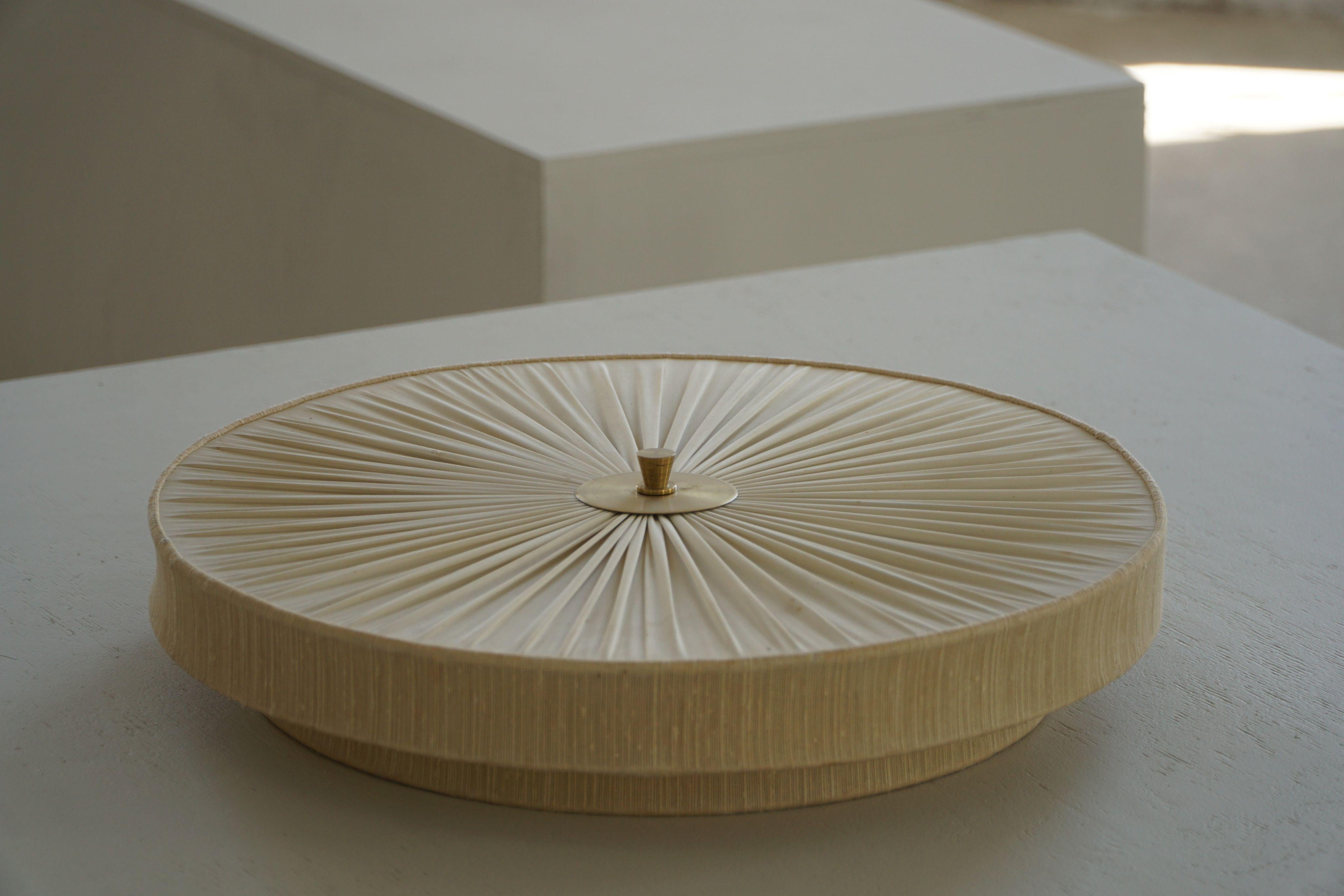 A beautiful round ceiling/wall sconce made of silk & brass. Made in Sweden in the 1960s, with a great sense of simple elegance, characteristic of the Swedish Mid Century era. The fixture features a circular shape creating a soft and sophisticated
