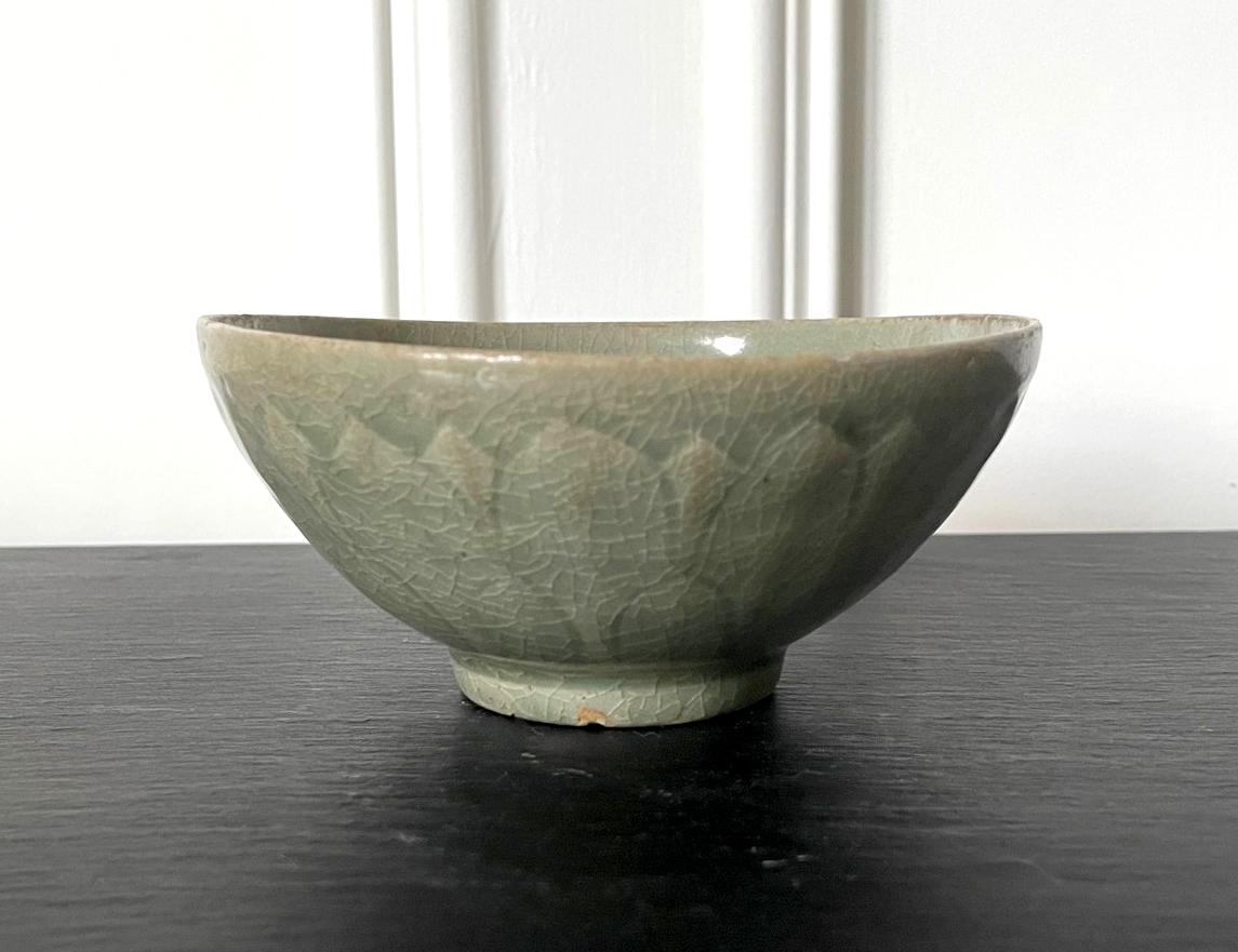 An antique Korean ceramic bowl with celadon glaze from Goryeo Dynasty circa 12th-13th century during the artistic zenith of the ceramic production. The stoneware bowl was potted delicately with hands and display a slightly irregularly shape viewing