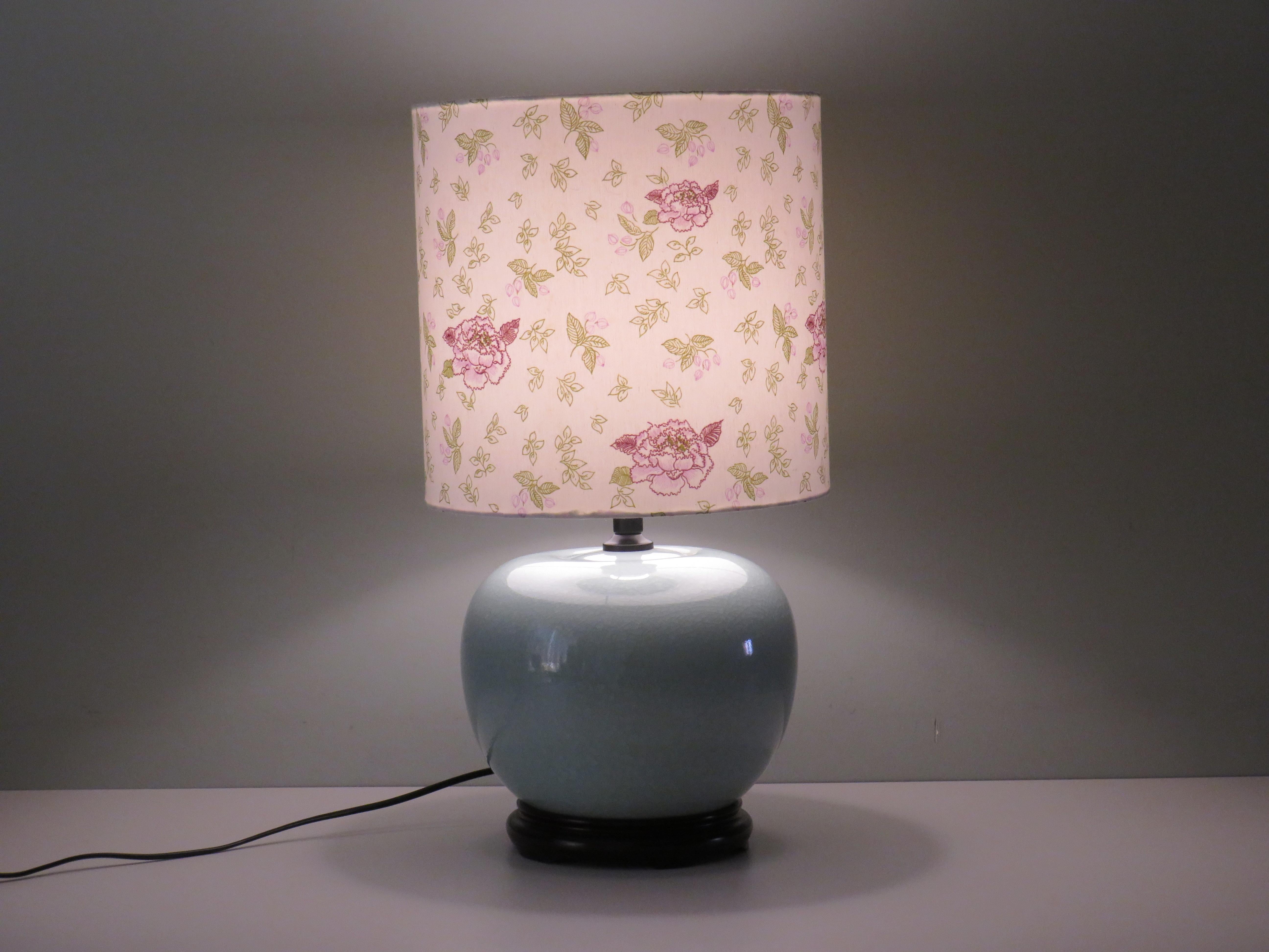 Lamp base made of glazed celadon-colored ceramic with crackle on a black wooden base.
The lampshade is custom made from a cotton fabric with burgundy, pink and green flower and leaf motifs on a white background.
The lampshade is 29 cm high and has