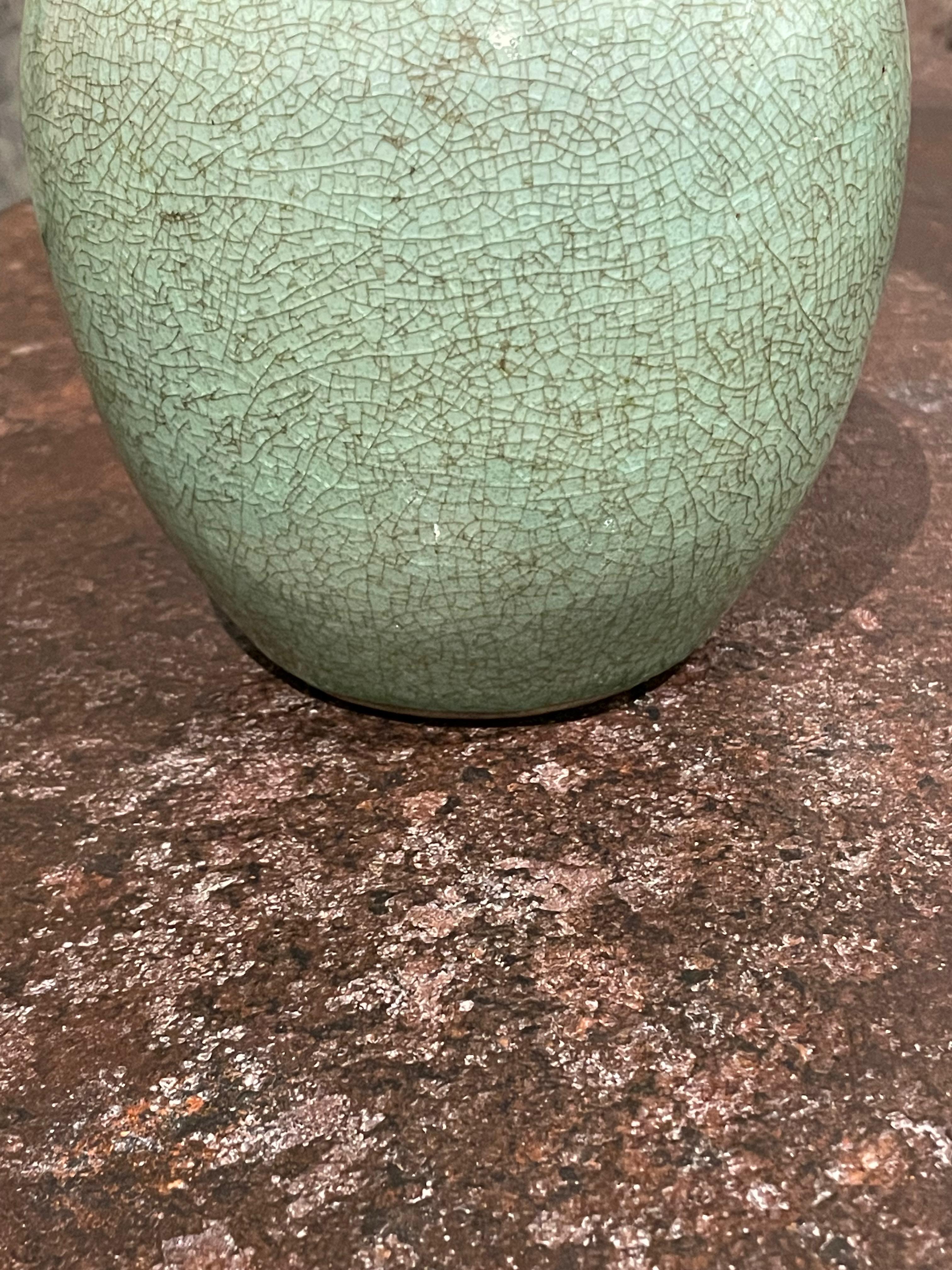 Contemporary Chinese small celadon crackle glaze vase.
Contrast tan band at opening.
The crackle glaze gives the vase the appearance of a vintage vase.