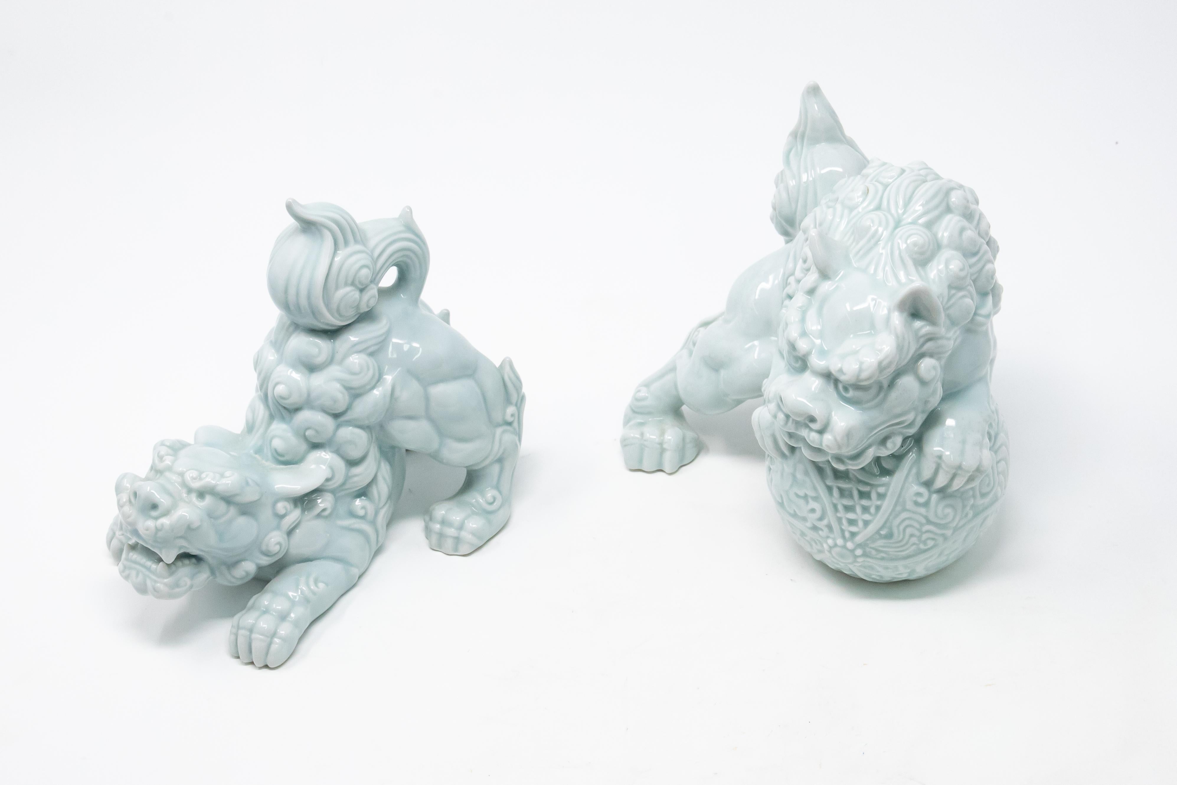 Offering this beautiful pair of Andrea by Sadek Celadon foo dogs. Gorgeous light turquoise color these are sure to stand out wherever you choose to put them. One is in a downward dog position that is playful. The other it perched with its front legs